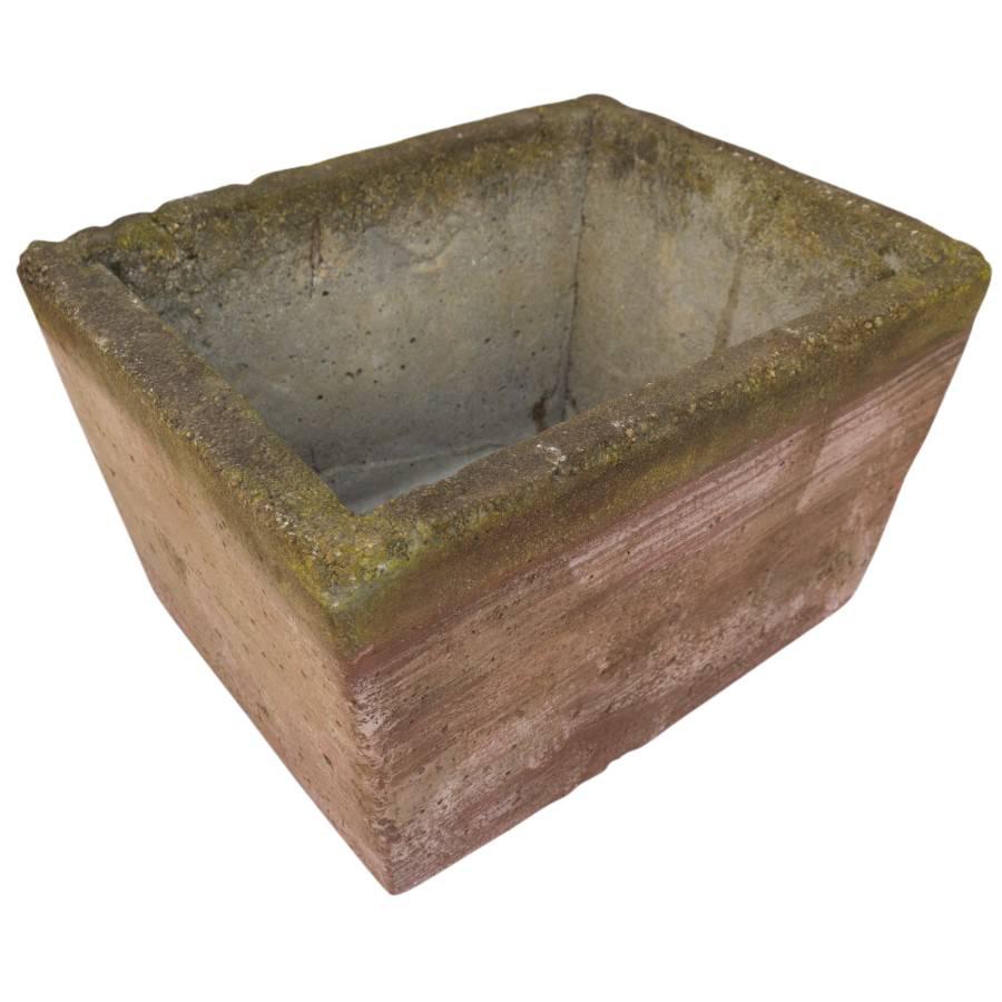 This heavy cement rectangle planter in handmade in France in the 1970s. The paint that red and yellow paint color that shows through is dulled from years of sunshine and use as a planter. You can see rich textures of cement underneath the paint.