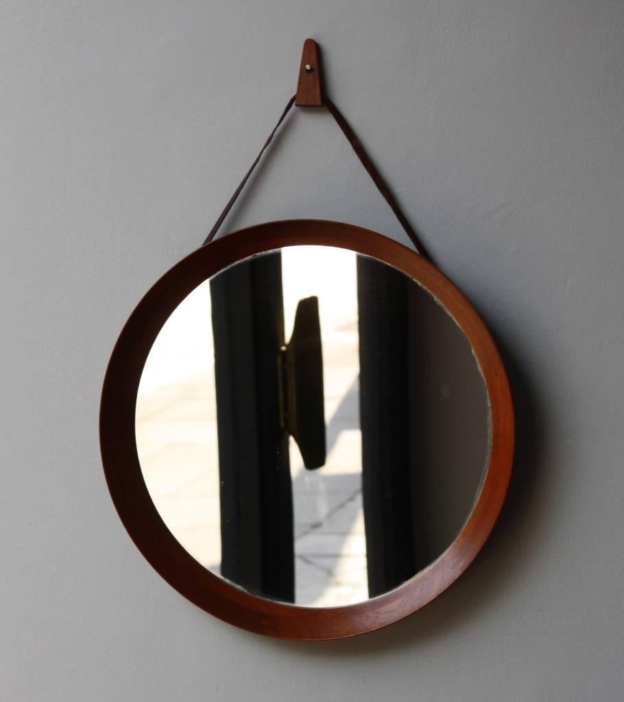 Round mirror made in Denmark, circa 1950. In rosewood of a light color due to exposition to light, it hangs with a triangular rosewood hook attached to the back to a leather cord. The frame is tapered and obtained joining several pieces of carved