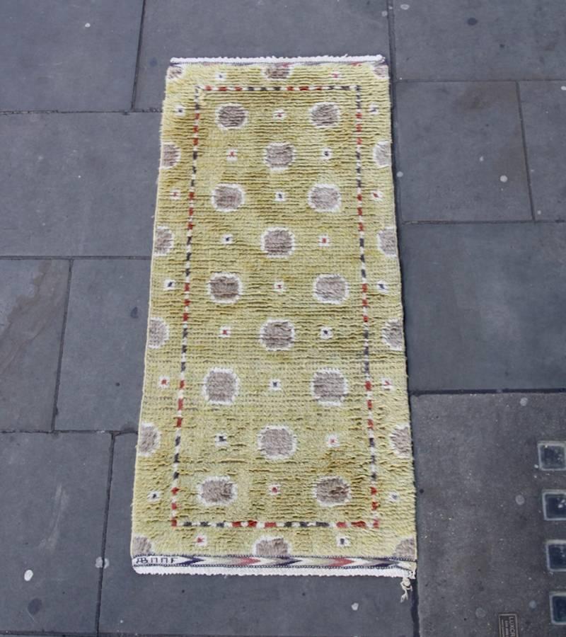 A vintage Rya rug by Barbro Nillson and Marta Måås-Fjetterström, Sweden, 1950s.
The pattern consists in the repetition of grey imperfect circular shapes with an off white contour, on a yellow background.
Four red and blue dots with the same white
