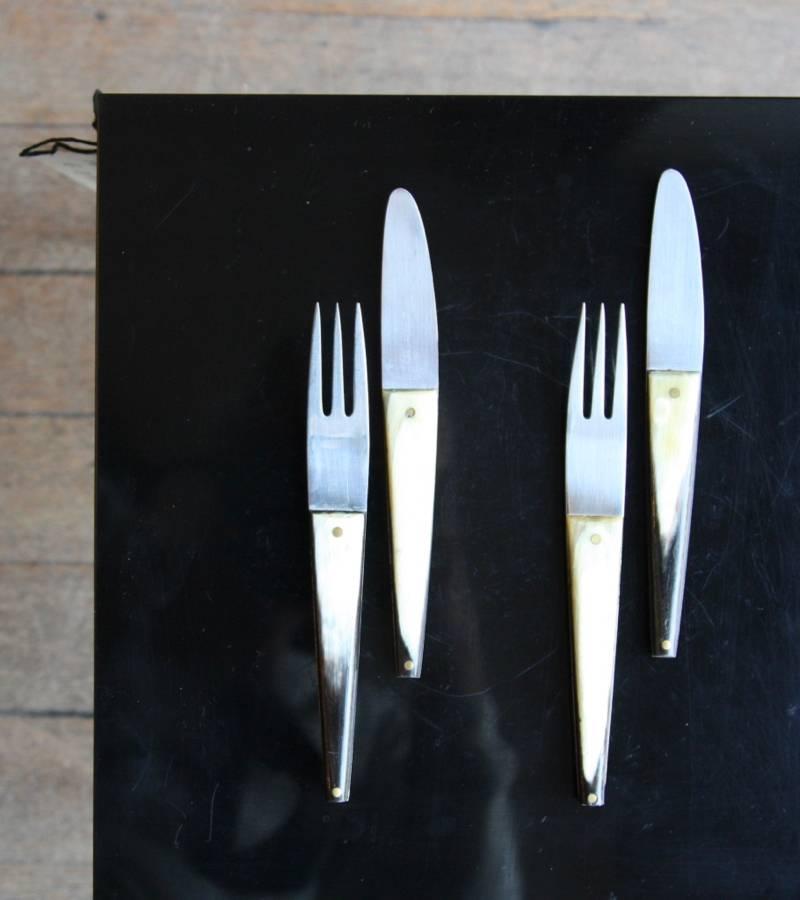 Vintage set of two forks and knives by the Auböck Workshop, Vienna, circa 1950. 
Made in stainless steel, each piece has an handle in Horn, attached to the steel body through two brass pins.
In excellent condition.