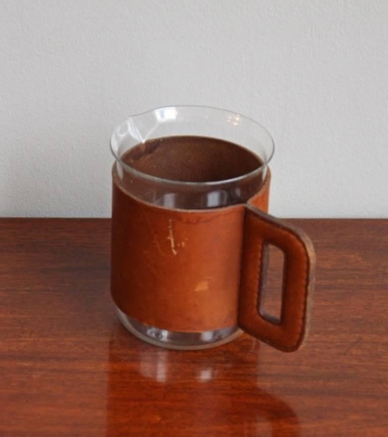 Great glass pitcher with a natural cognac leather handle and cover.