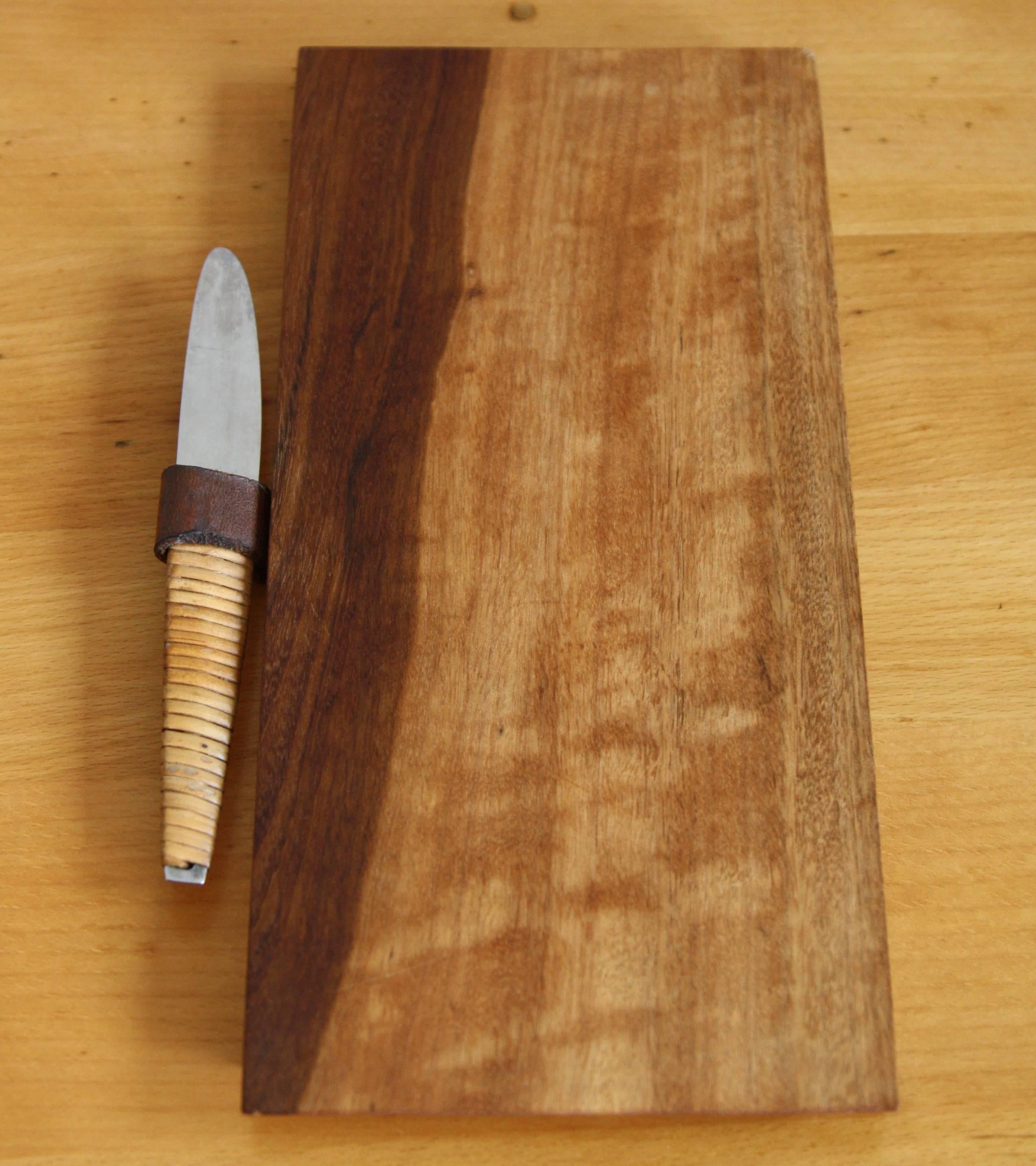 Vintage cutting board set designed and made by Carl Auböck. The walnut wood board is geometrically carved whilst the wrapped cane wrapped stainless steel knife is more organic in shape. The leather holder elegantly marries them together.