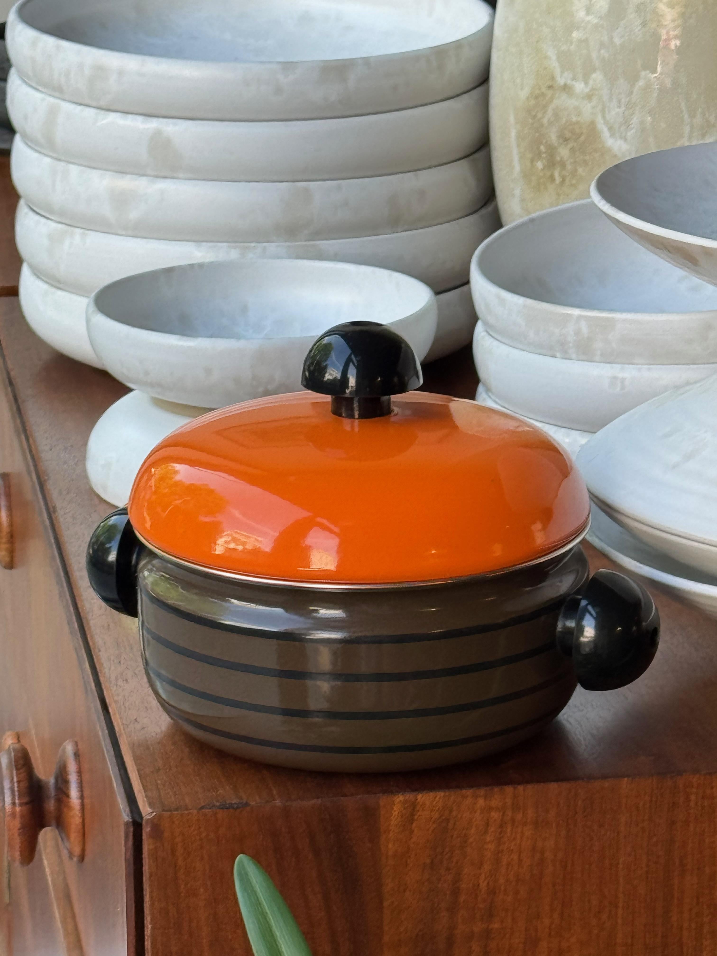 Description:

An enamelled metal pot, designed during the 1970s by Carl Auböck III during the 1970s.

Suitably seventies with its vivid orange lid and graphic striped profile, this enamelled metal pot was part of a series of cookware designed by the