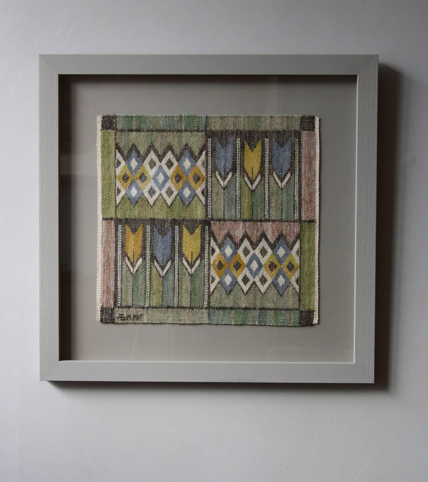 A vintage mid-20th century handwoven textile from Marta Maas-Fjetterström’s workshop in Båstad, Sweden, designed by Barbro Nilsson.
The tapestry features geometric diamonds and rectangles as well as six tulip flowers. The symmetrical arrangement
