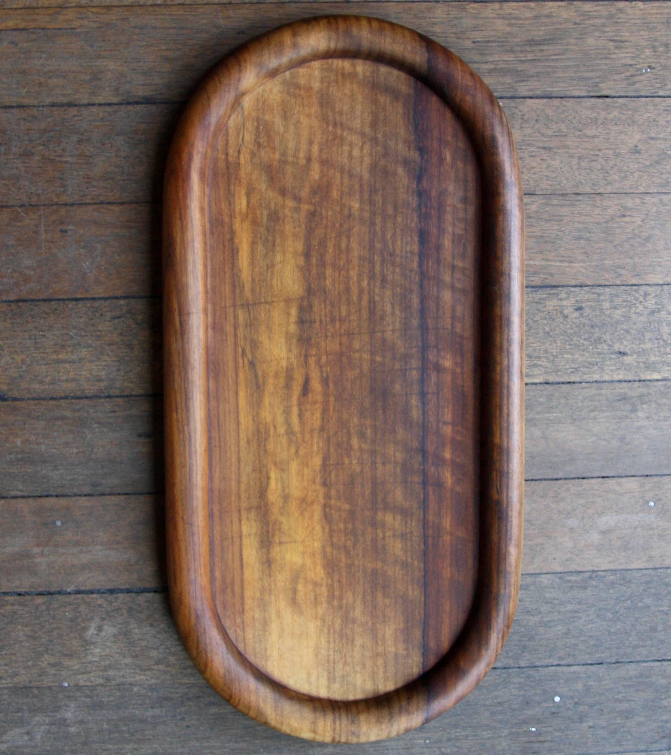 A large cutting board or serving tray in solid walnut. The sculpted platter was designed and made by Carl Auböck III at the Auböck werkstätte in Vienna in the 1980s. The thick but flowing rim to the piece makes it ideal for use as a cutting board as