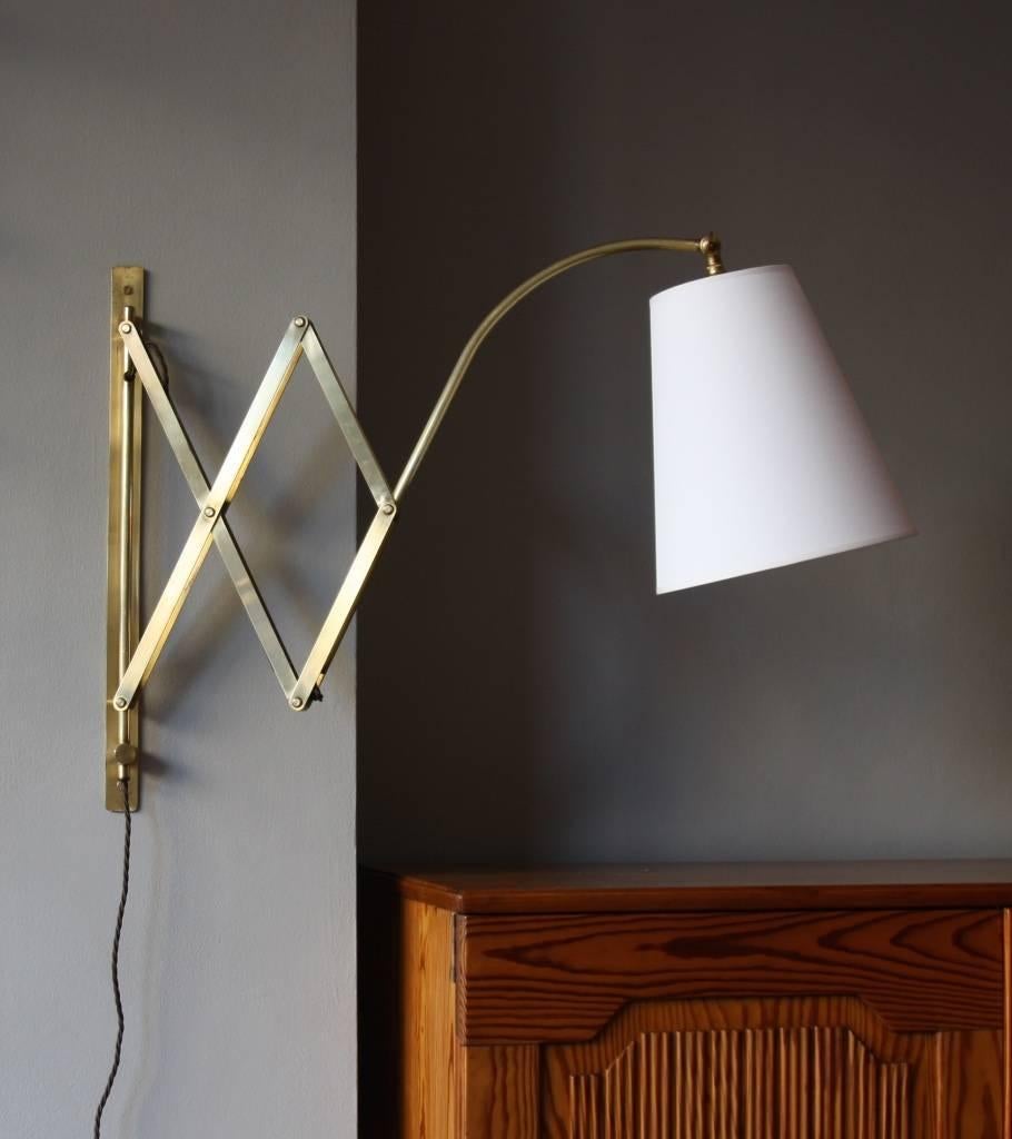 Large concertina wall light in polished brass designed and made in Denmark in 1950s.
The arm extends up to 90 cm and rotates around the wall support; the head is covered by a newly made cotton shade with a frame in copper coated