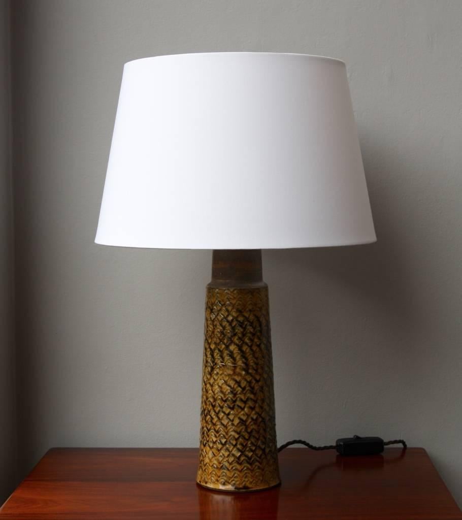 Table lamp by Nils Kähler designed and made in Denmark in 1960s.
The stoneware body is glazed in a glossy ochre glaze and decorated with herringbone pattern both the glaze and the pattern, as well as the cylindrical tapered shape, are signature