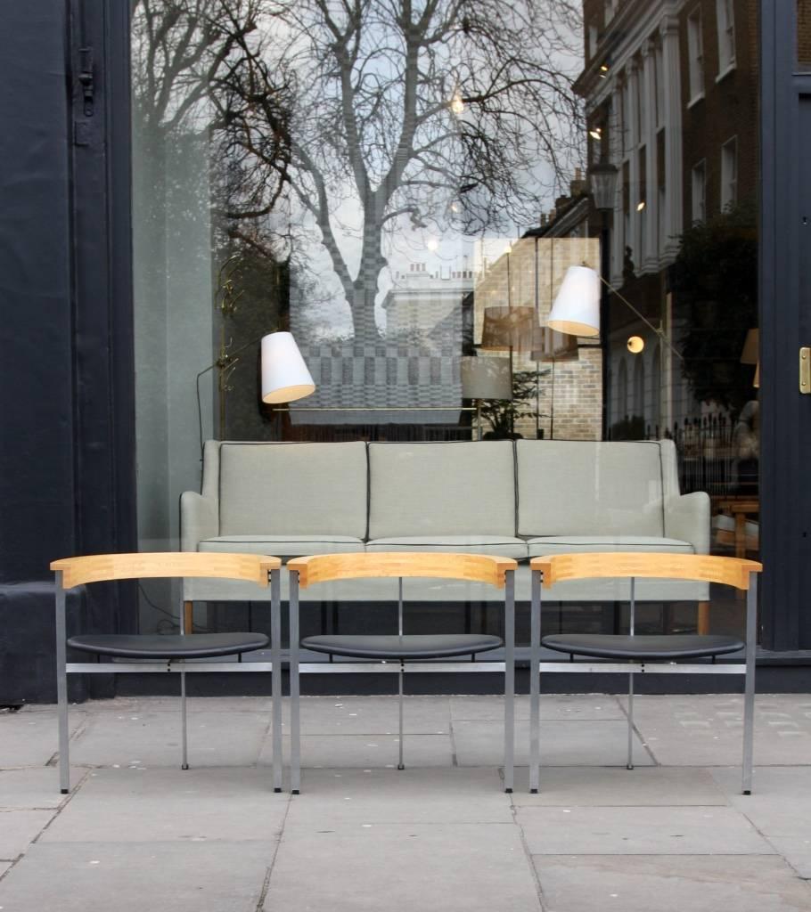Set of three PK 11 armchairs by Poul Kjærholm.
Originally designed in 1957 to go with the PK 51 desk, the PK 11 has a three-legged satin brushed stainless steel frame supporting a black leather seat and a semi-circular back in ash.