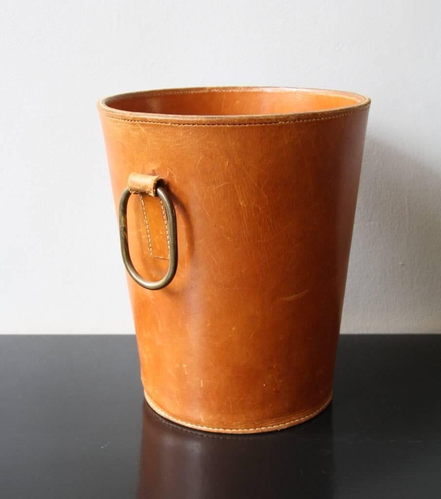 Vintage paper basket manufactured in the 1950s in the Auböck Werkstätte in Vienna. The basket is made of two pieces of leather sewn up with white stitching and has a polished brass handle. In good condition.