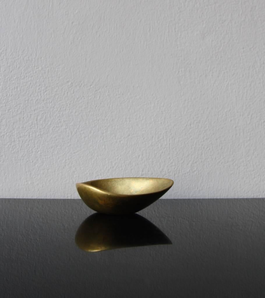 A vintage brass ashtray shaped like an half chestnut designed and made by the Auböck Werkstatte, Vienna, circa 1950.
Covered by a uniform patina naturally built over time, the tiny ashtray has a slender, asymmetrical and very delicate