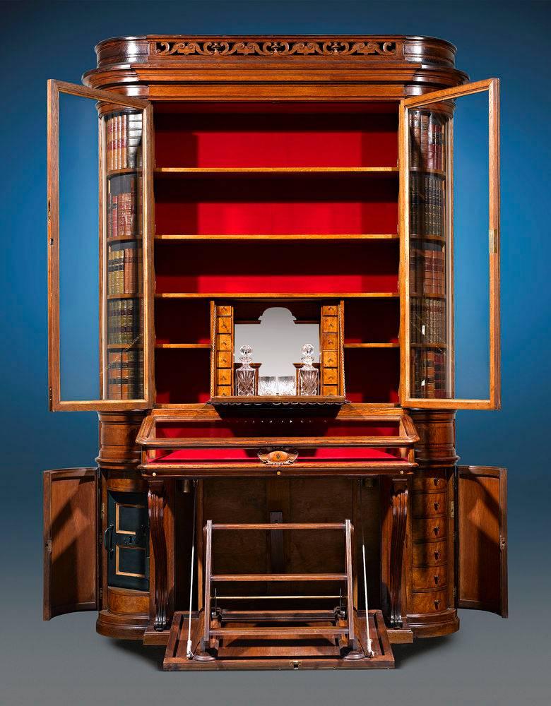 This oak cabinet is an English masterpiece of both cabinetmaking and mechanical engineering. Standing at nine-feet high and displaying all of the aesthetic hallmarks of the Victorian era, the finely carved oak cabinet appears to be the perfect place