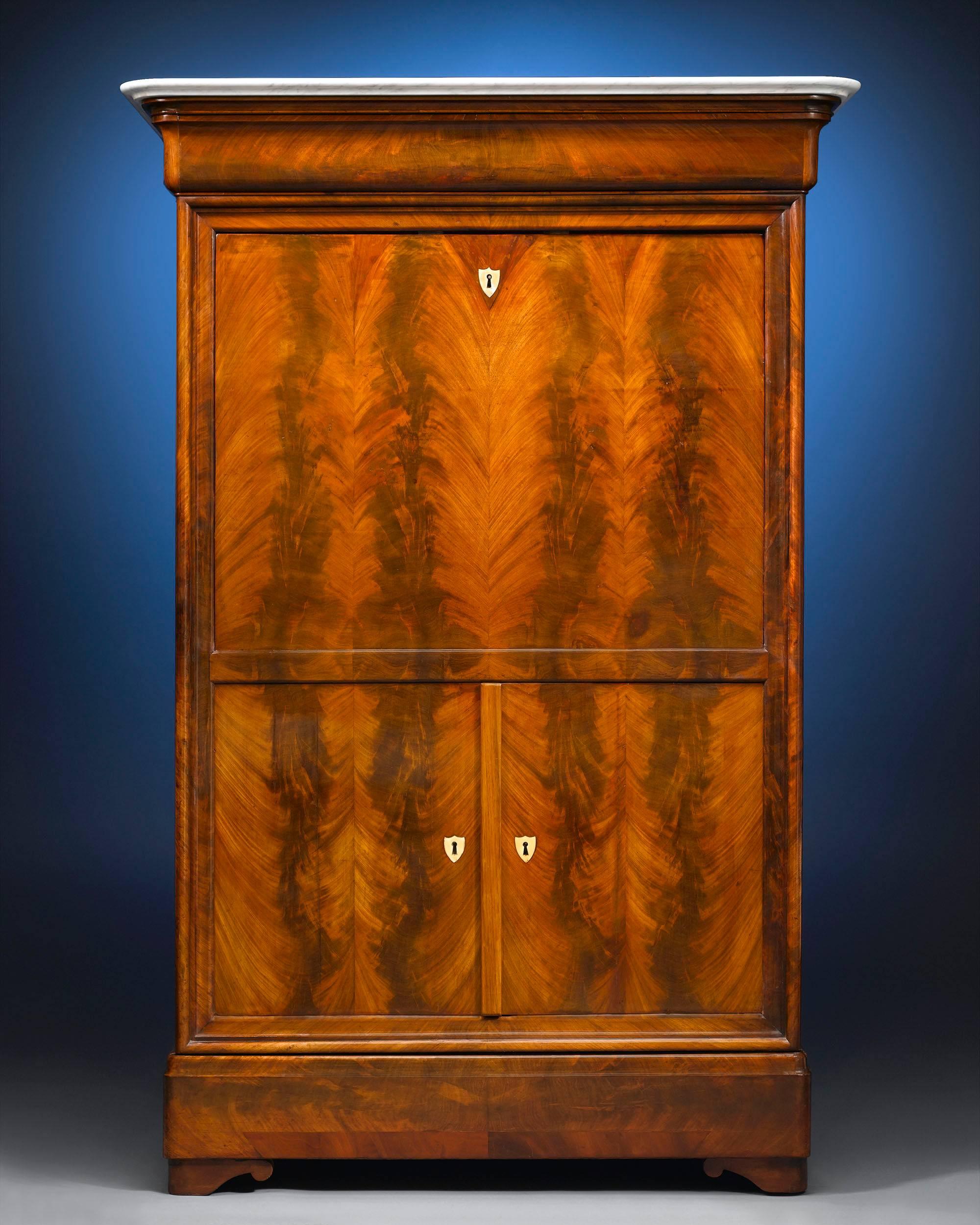 Both practical and eye-catching, this handsome Louis Philippe secrétaire à abattant is beautifully crafted of the finest materials. Perfectly matched Cuban mahogany panels and a white Carrara marble top distinguish this piece's Classic exterior,