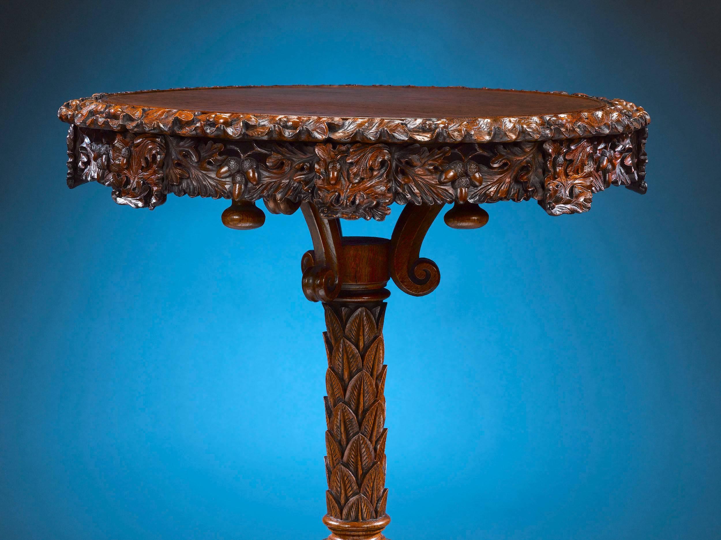 The exquisite, deep carving of this fine oak Lazy Susan occasional table is consistent with the masterful cabinetmaking associated with the famed S.J. Waring firm of Liverpool. Standing upon a tripod base terminating in paw feet, the top of the