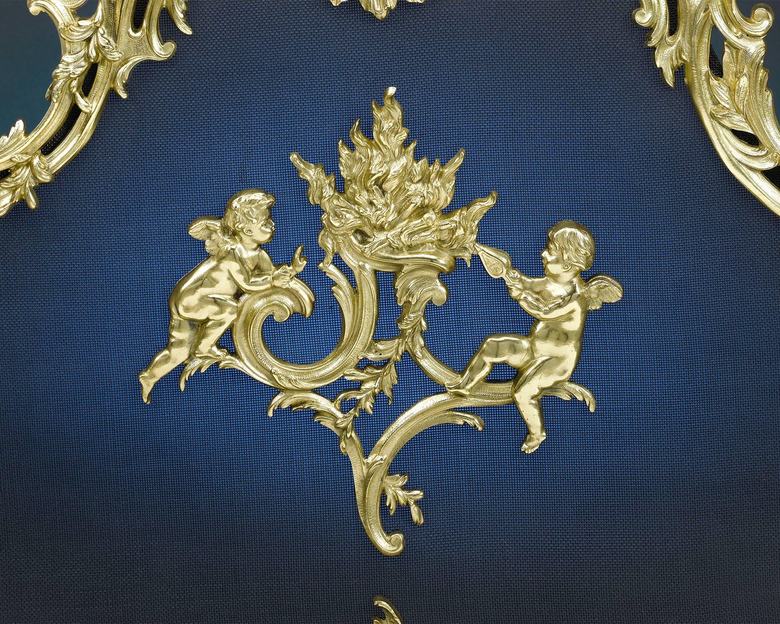 This exceptional gilt bronze and mesh French fire screen will add elegance to any hearth. The elegant Rococo style form is composed of detailed scrolls and vines, and the mesh panel centered with a playful gilt bronze putti appliqué. A foliate cast