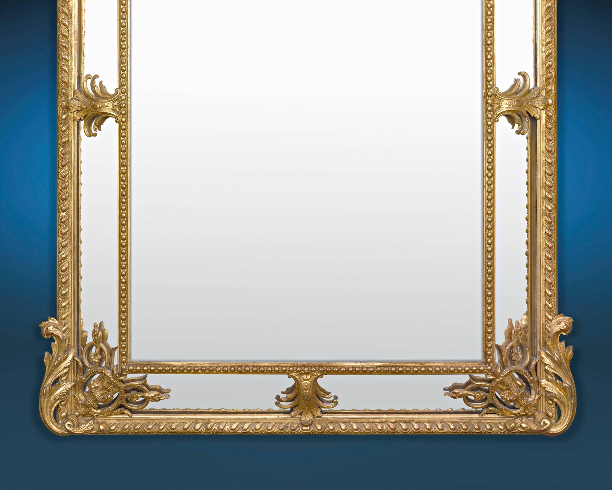 This stately Louis XV Revival French mirror features and elegant and intricately carved giltwood frame. The mirror is a study in Rococo glamour, with its asymmetrical, foliate decoration, C-scrolls, and cherub and bird accents. Highly unique and