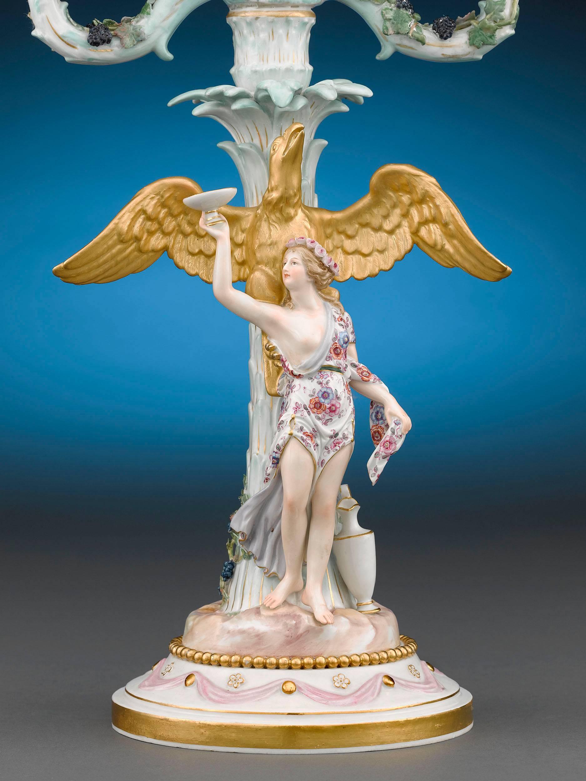 This outstanding pair of two-light Meissen candelabra is inspired by Greek mythology. Crafted with the exquisite detail for which Meissen is renowned, the lights depict Hebe and Ganymede, the two cupbearers to the gods, standing beneath palm trees