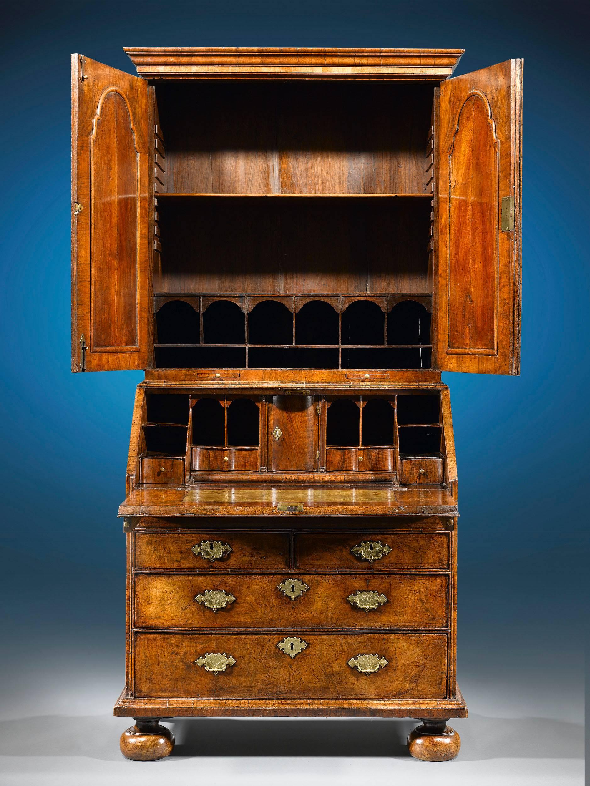 Queen Anne period furnishings such as this walnut secretary are incredibly rare and important examples of English cabinetmaking. This secretary is of the most outstanding caliber, boasting desirable double bonnet, mirrored cabinet doors and later