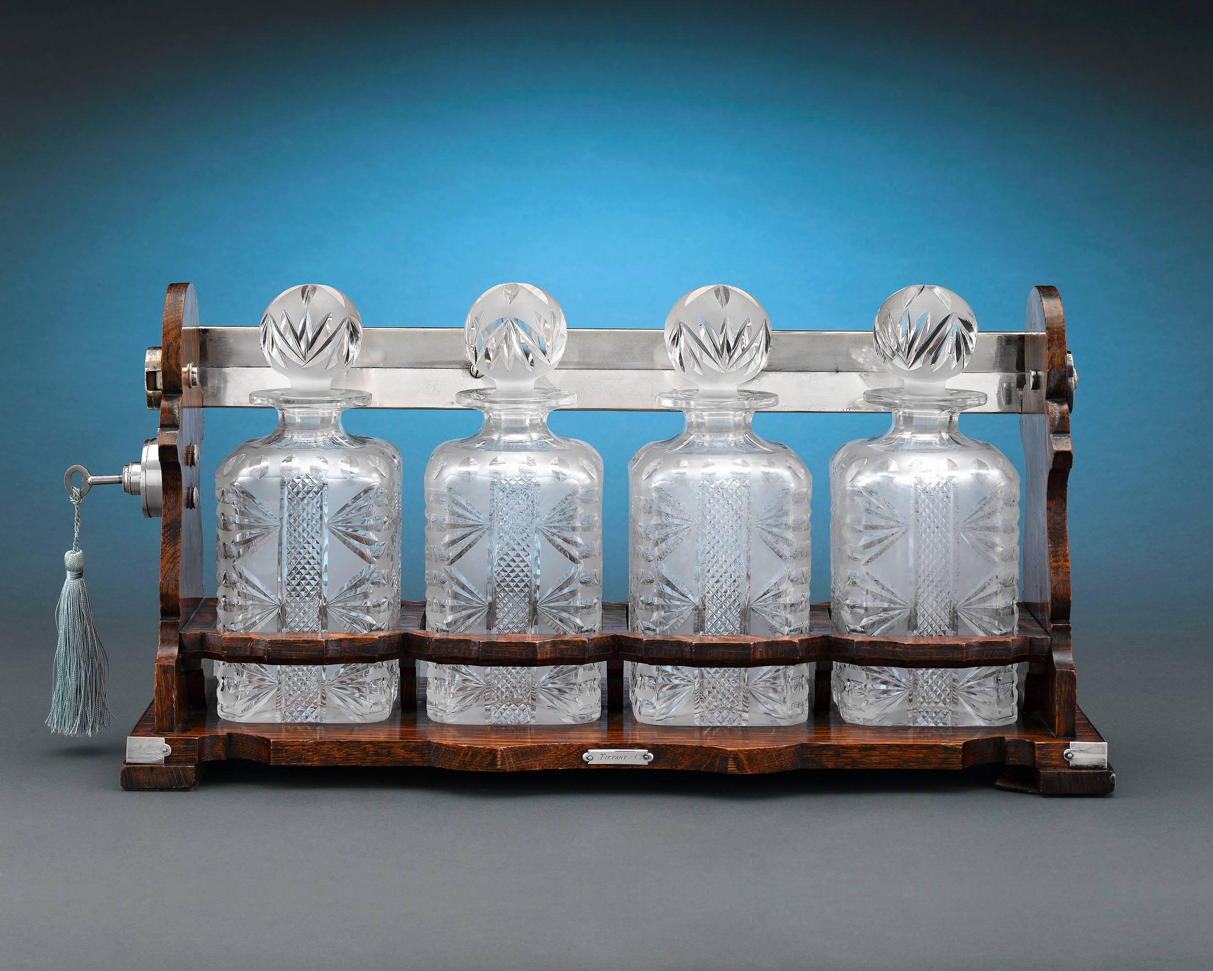 Retailed by Tiffany & Co., this rare and wonderful tantalus was patented by Netherlander cabinetmaker George Betjemann in 1881. Typically containing two or three crystal decanters, this particular model holds four, and is crafted of fine oak and