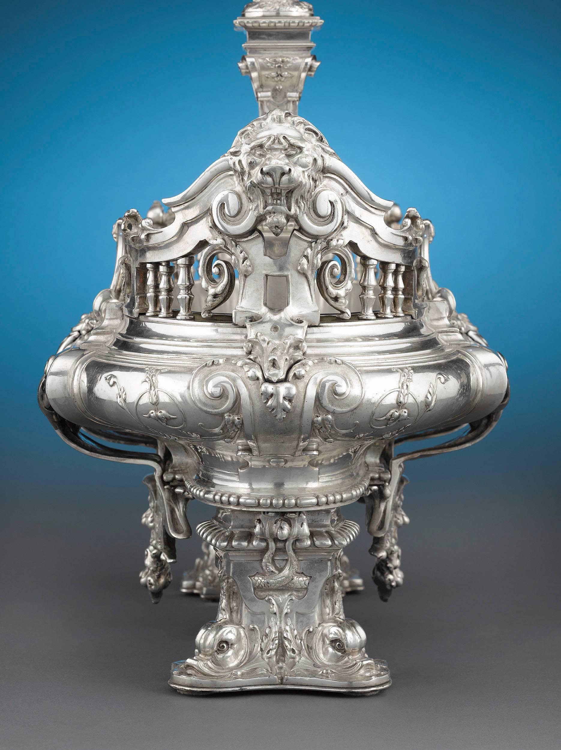 A truly exceptional example of continental silver plate, this French centerpiece is formed in the exuberant Troubadour style. The oval form is adorned with drapery swags and ornate balustrade ends surmounted by lion masks, which flank a putto