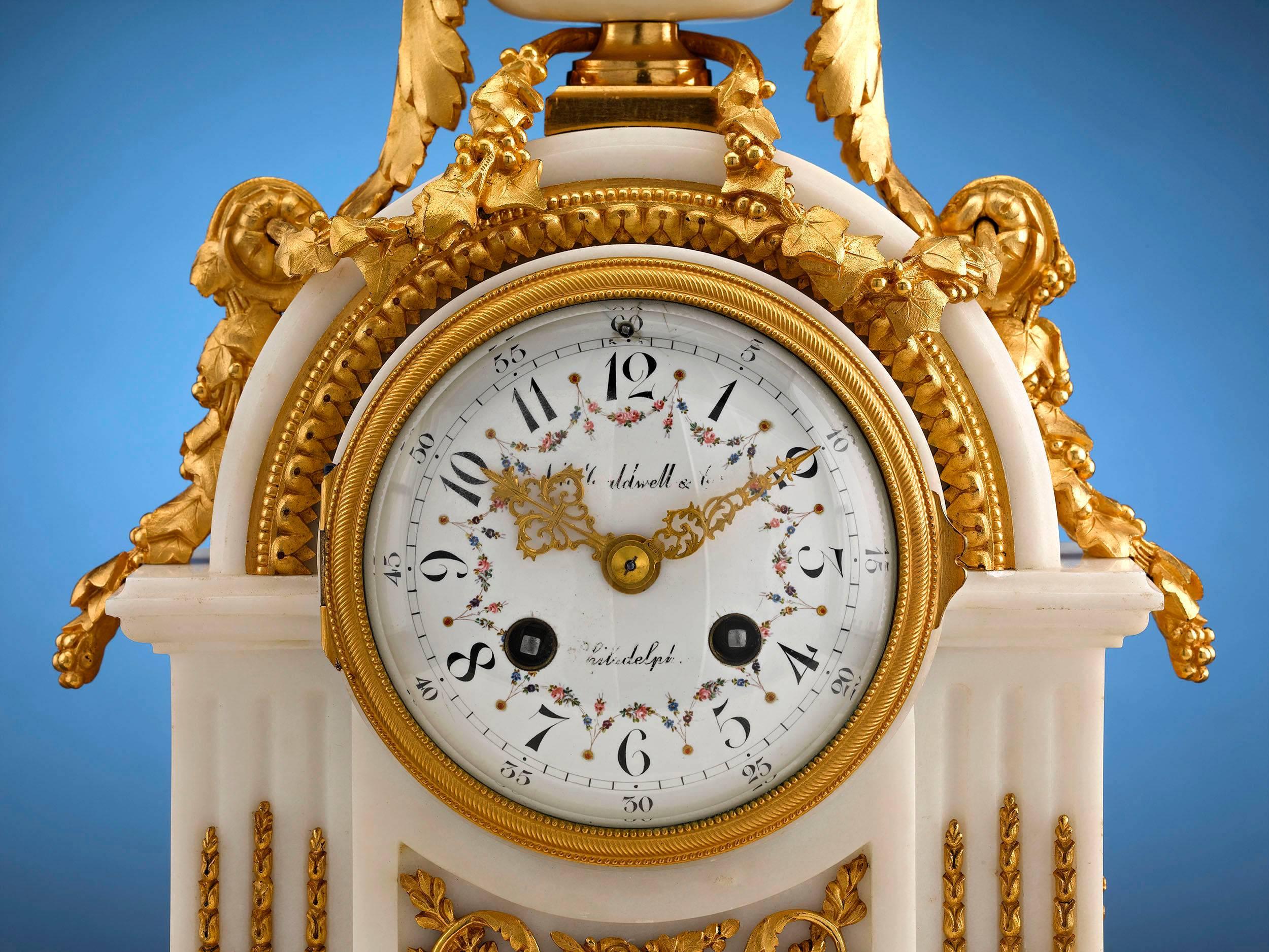 This stunning mantel clock by J. E. Caldwell & Co. of Philadelphia exudes tasteful elegance. Crafted of luxurious marble in the French Louis XVI-style, this stunning timepiece boasts cast doré bronze adornments, from the harvest finial and