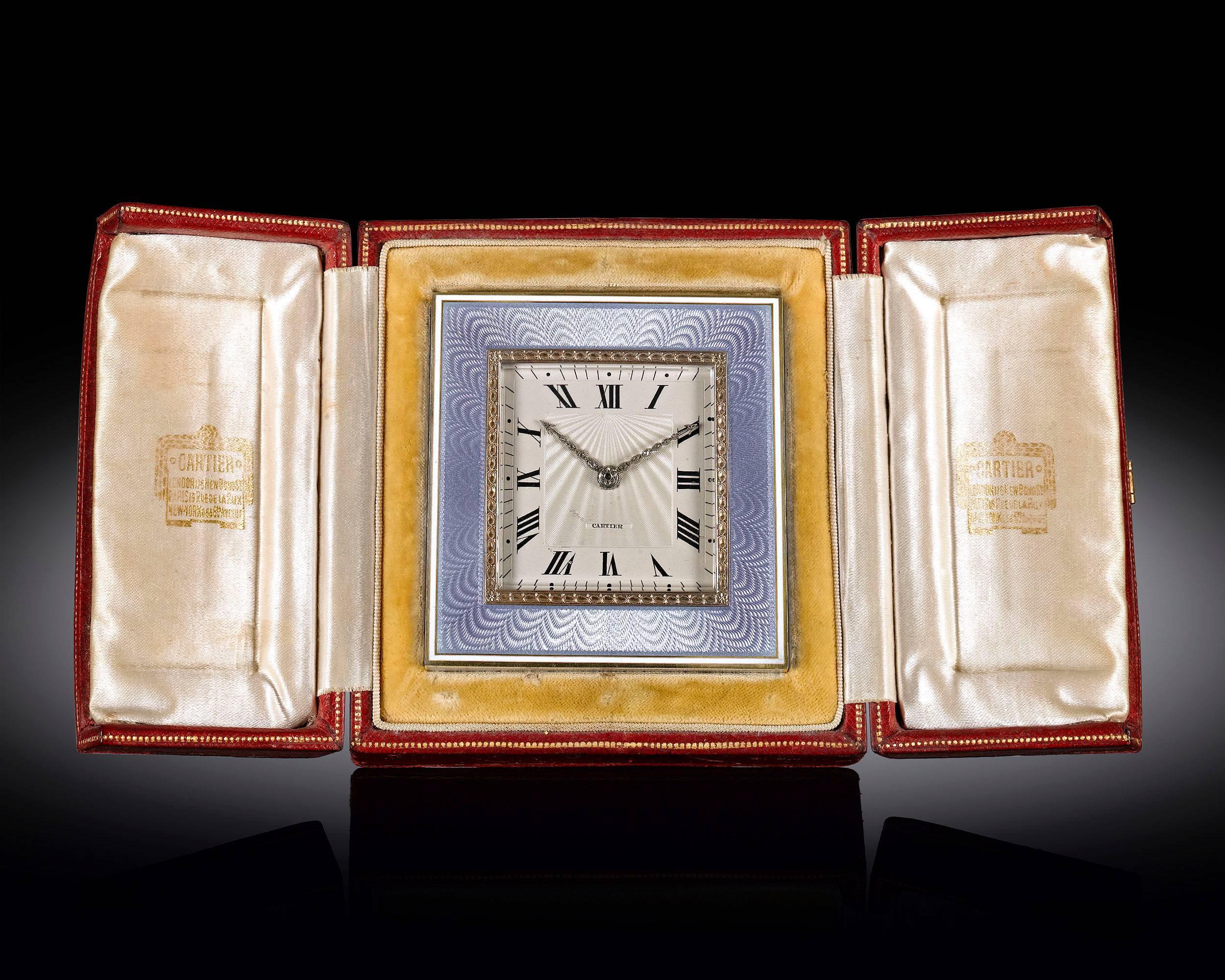 This elegant desk clock by Cartier features a soft blue guilloché enamel and gold frame. With Roman numerals marking the hours, the dial's radiant guilloché pattern is well-complemented by hands studded with fine white diamonds. An outstanding