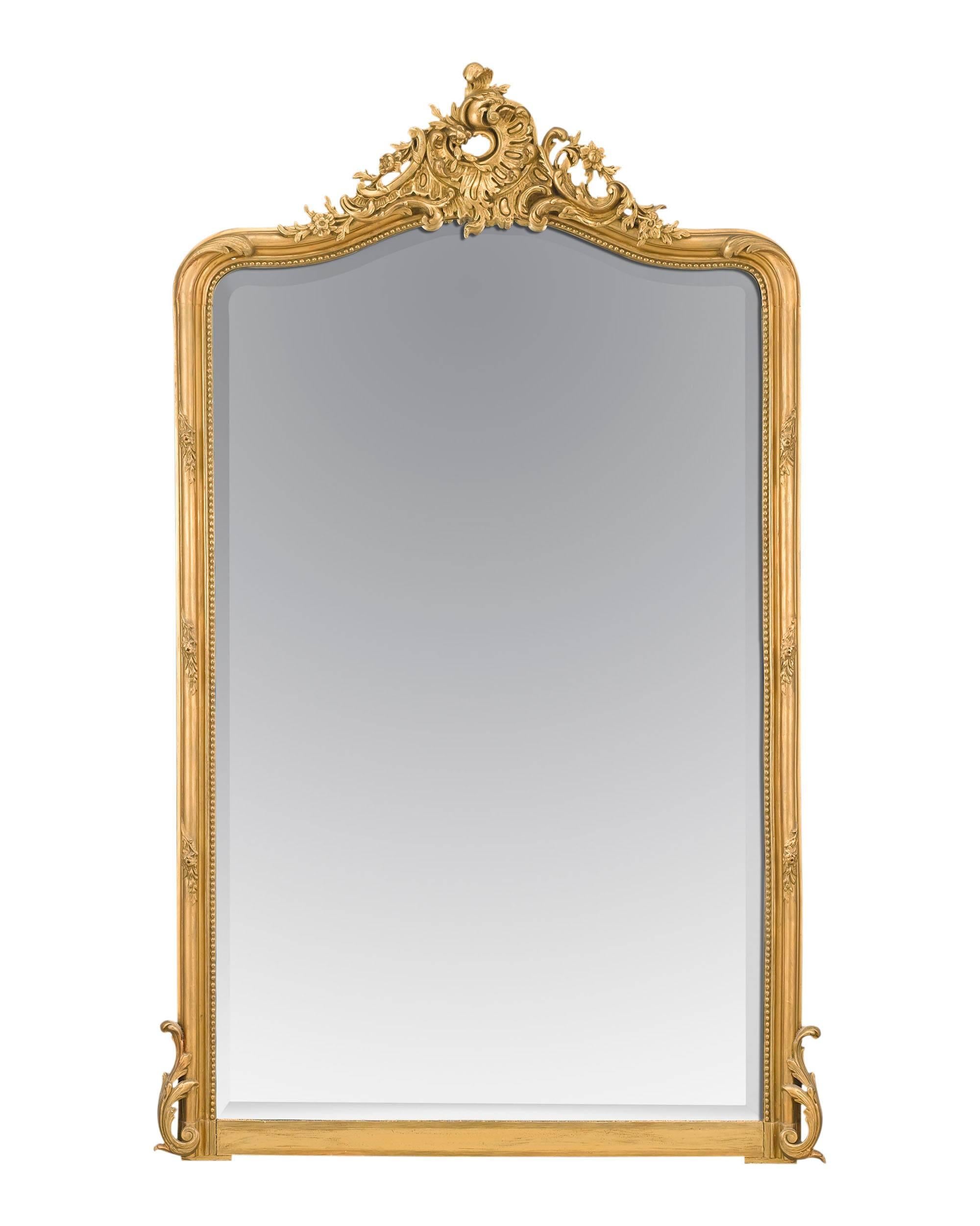 This stunning and very impressive gilt French mirror is of exceptional quality. Styled in the Louis XV fashion, the mirror features a heavy scroll relief and detailed beading that frames the beveled mirror. Displaying magnificent size, expertly