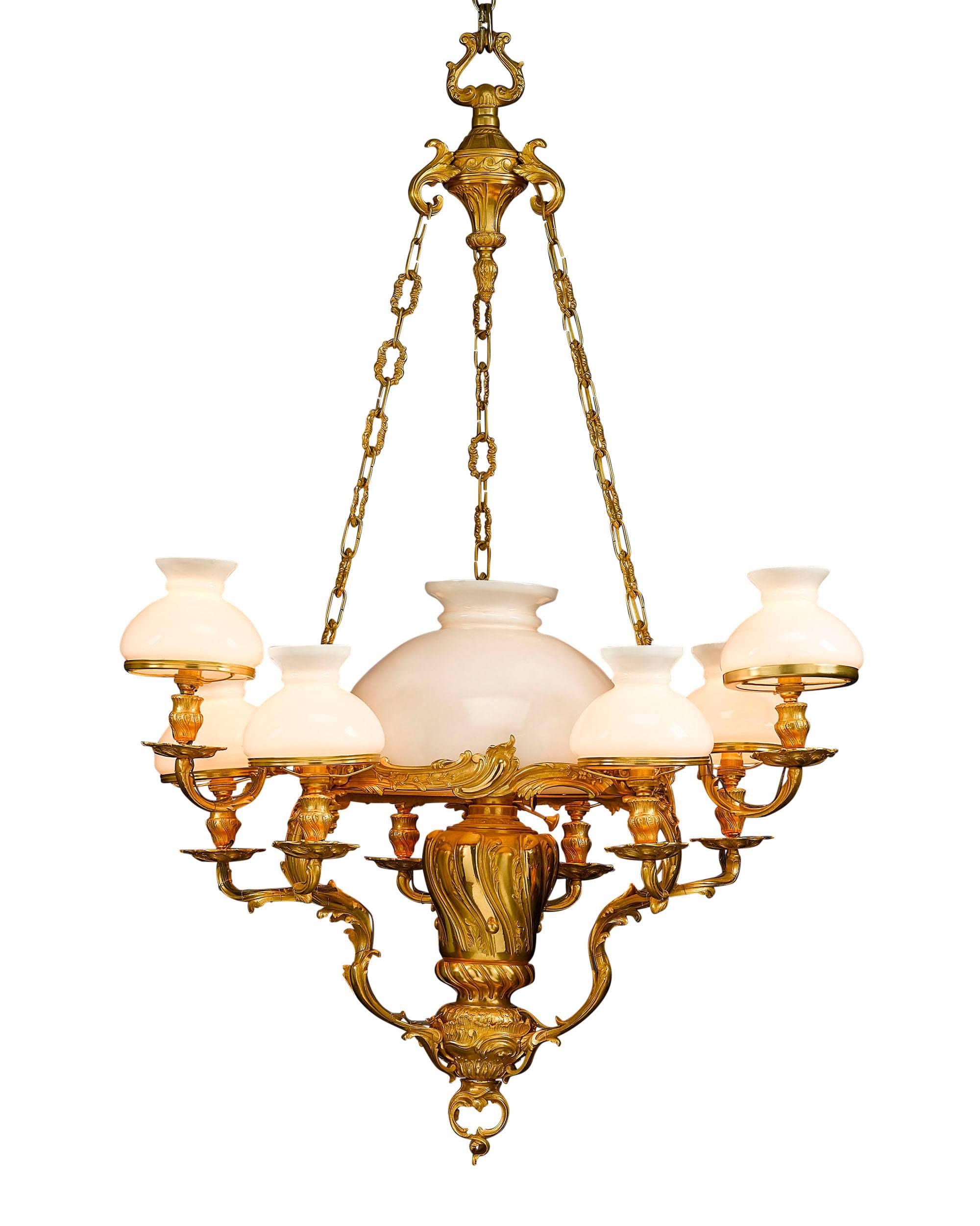 This refined ten-light chandelier is a grand example of 19th century French opulence. Crafted in the Louis XV style, this fixture emits a soft glow thanks to a large central light surrounded by three arms of three lights each, all shaded by frosted