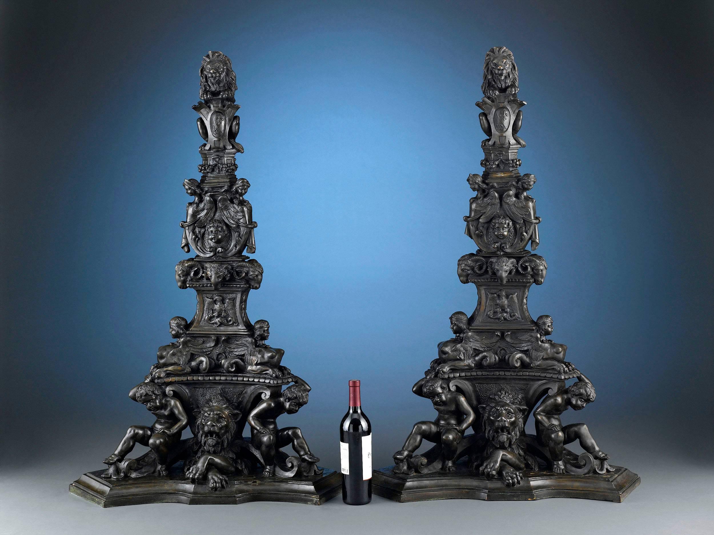 This monumental pair of Italian bronze andirons is among the most intriguing and heavily decorated we have ever seen. Standing 45 inches tall, the andirons exhibit sculptural work of tremendous detail and symbolism. The figures represented include