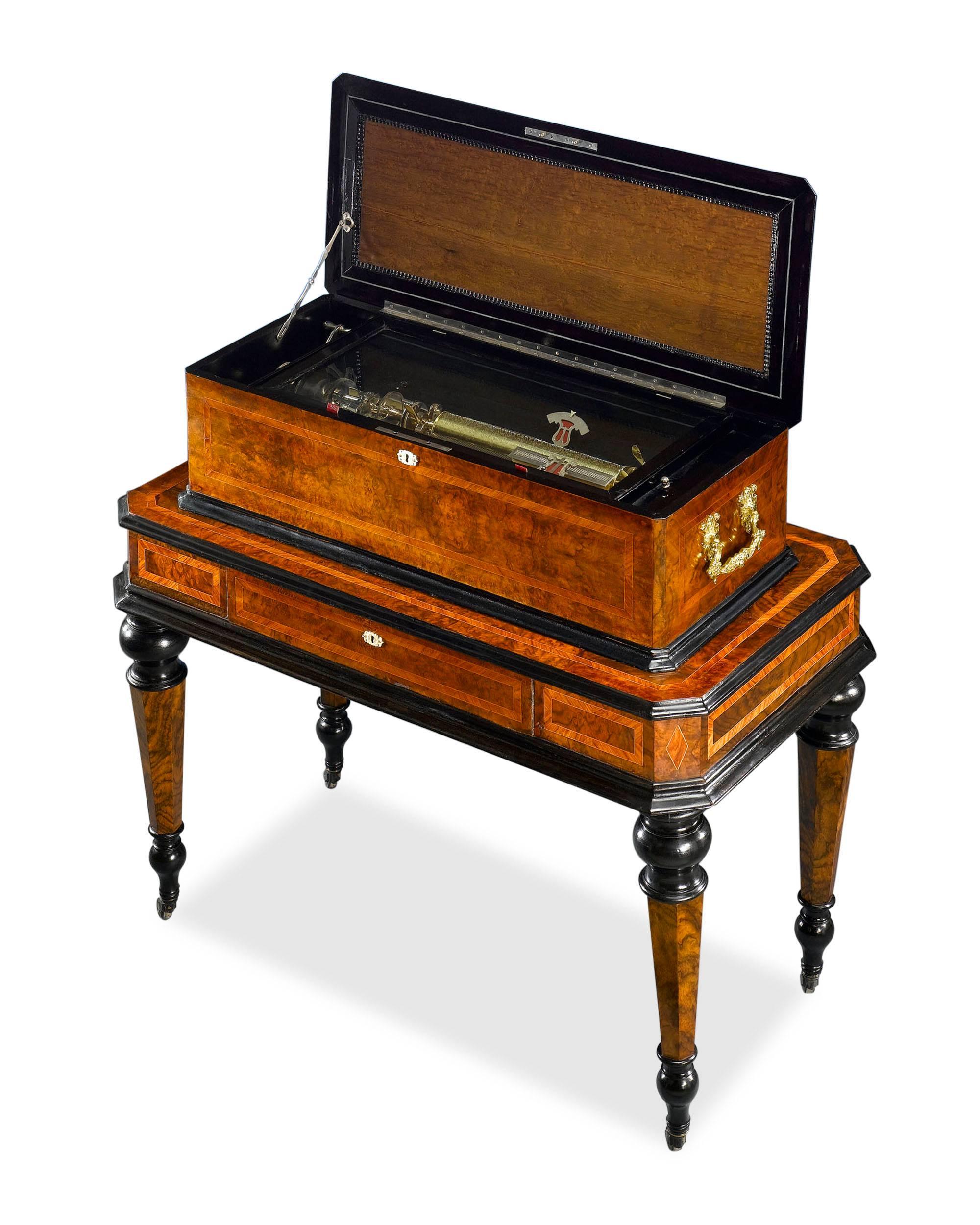 This captivating and exceptionally engineered Swiss interchangable cylinder music box is accompanied by its original table. The mechanism is set in a beautiful case of burled and ebonized walnut with satinwood, brass and mother-of-pearl inlays