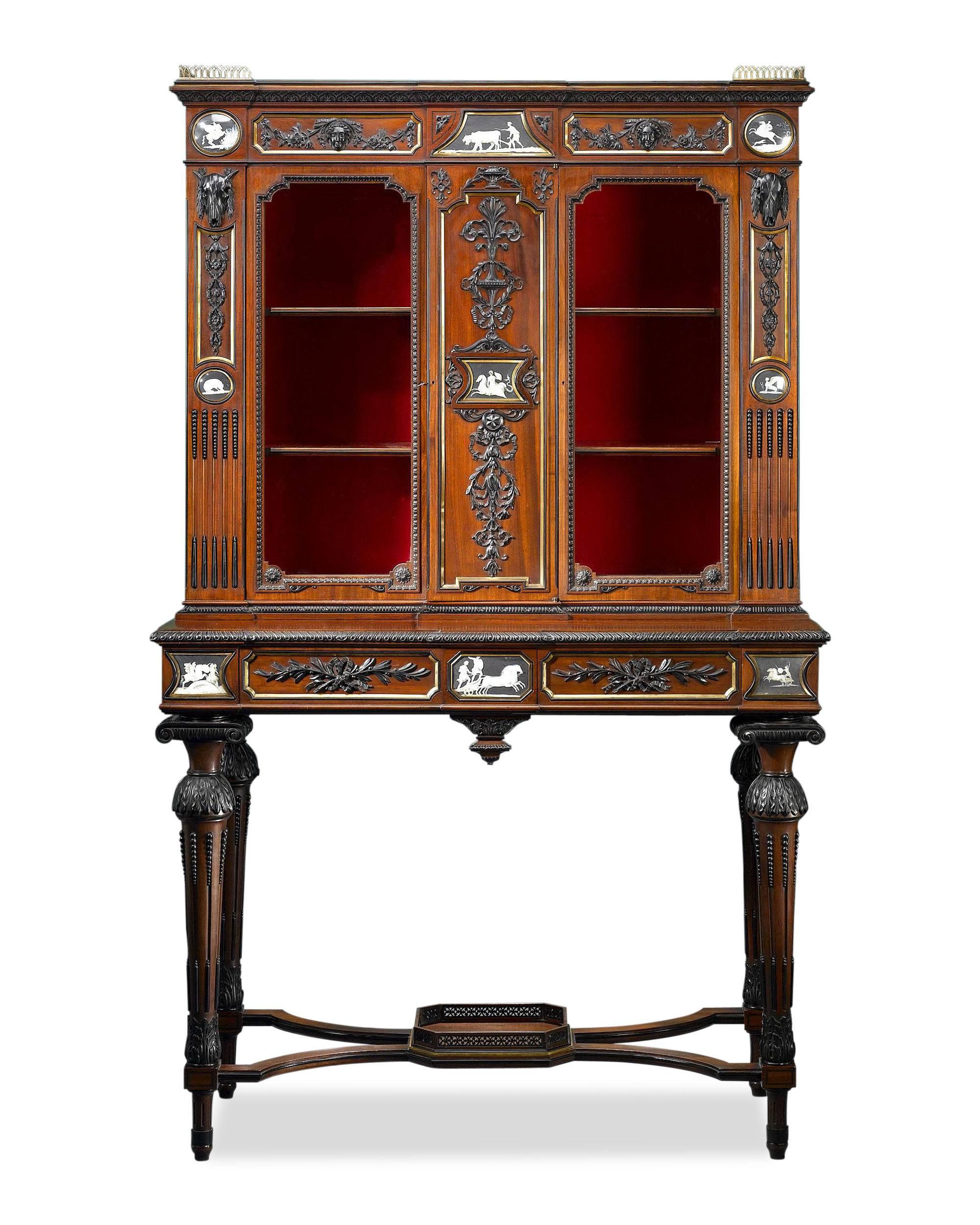 This important manhogany cabinet by English maker William Bertram of Dean Street, Soho, is crafted in the Etruscan style and handsomely decorated with wonderful hand-painted plaques and dramatic carved ebony accents. Each of the plaques depicts a
