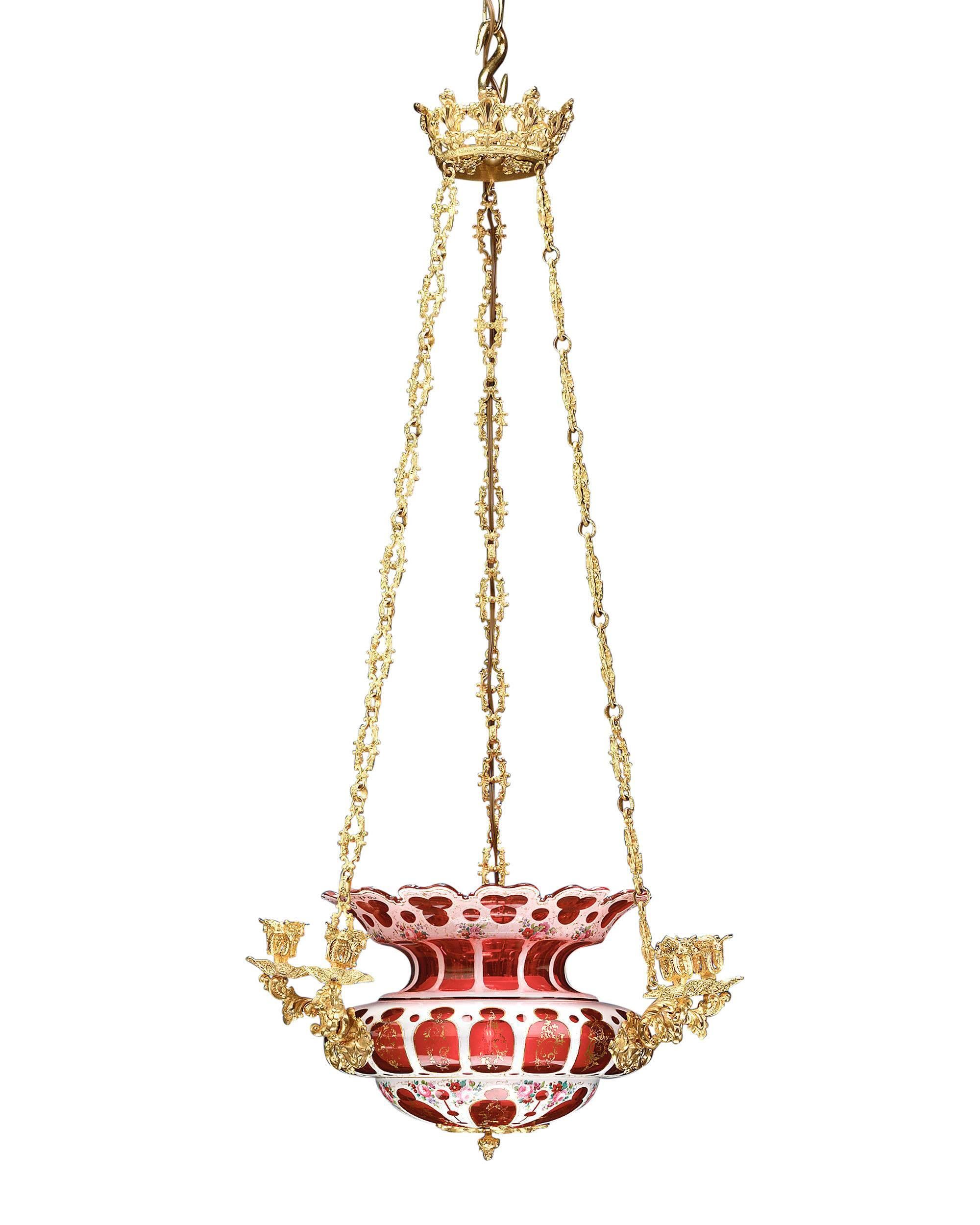 A beautiful chandelier of exquisite Bohemian overlaid ruby and white glass hand-painted with colorful floral sprays and gilt accents. The luminous center bowl hangs from a majestic doré bronze crown and is surrounded by six doré bronze candle