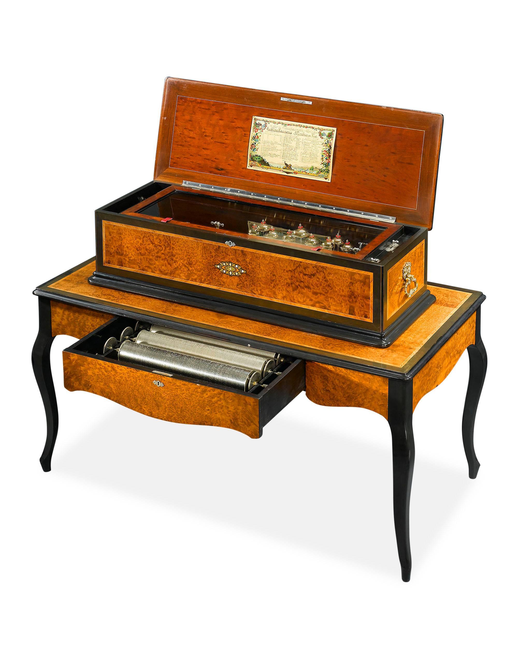A captivating and exceptionally engineered Swiss Sublime Harmonie six cylinder music box with matching table. Set in a beautiful case of burled walnut with satinwood and ebonized wood inlay, this piece serves not only as melodious entertainment but