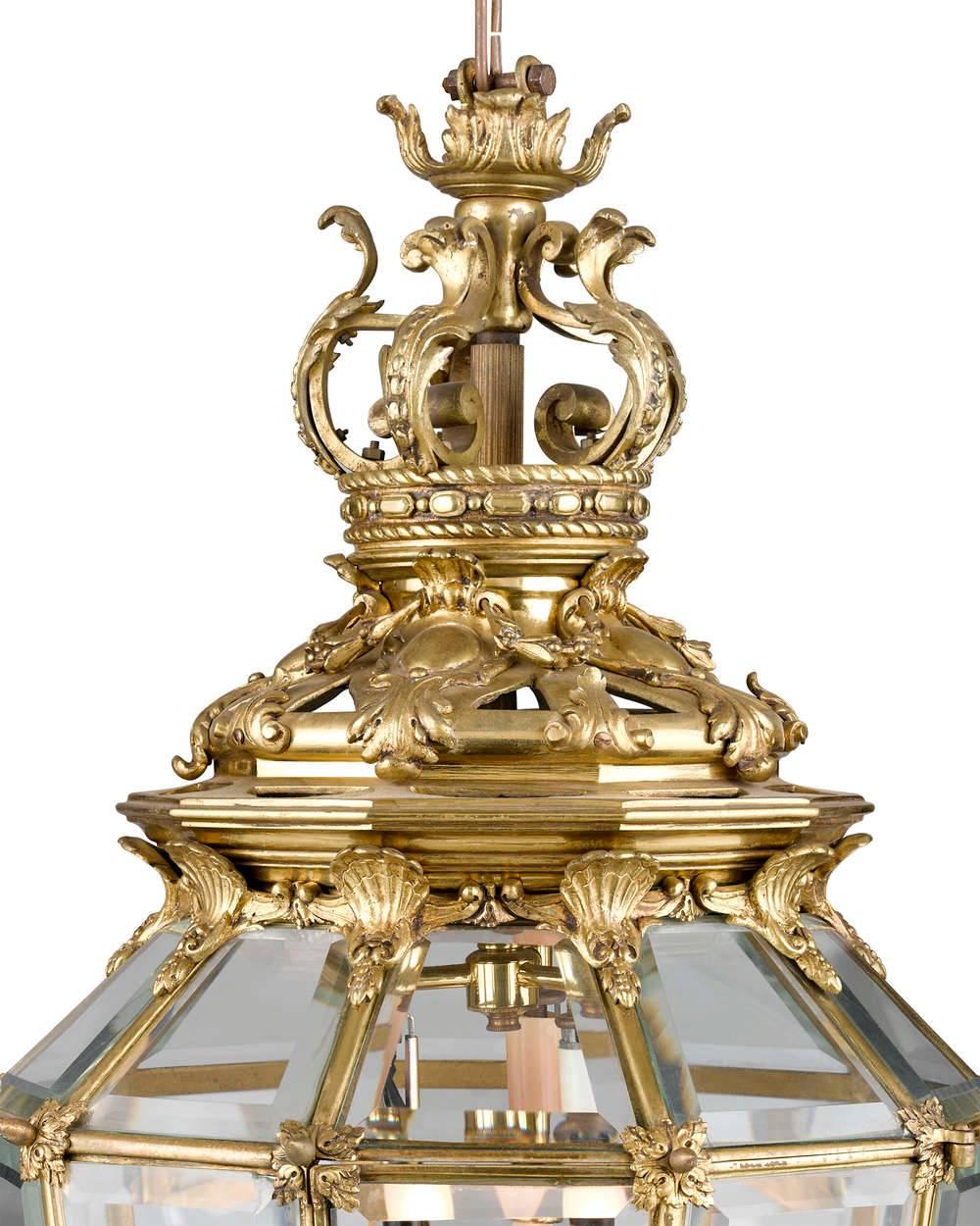 This grand doré bronze hall lantern was inspired by the model made for the Palace of Versailles. The expertly cast bronze is enveloped in beautiful gold gilt, highlighting the Louis XV motif rich in shells and acanthus elements. Beveled glass panels