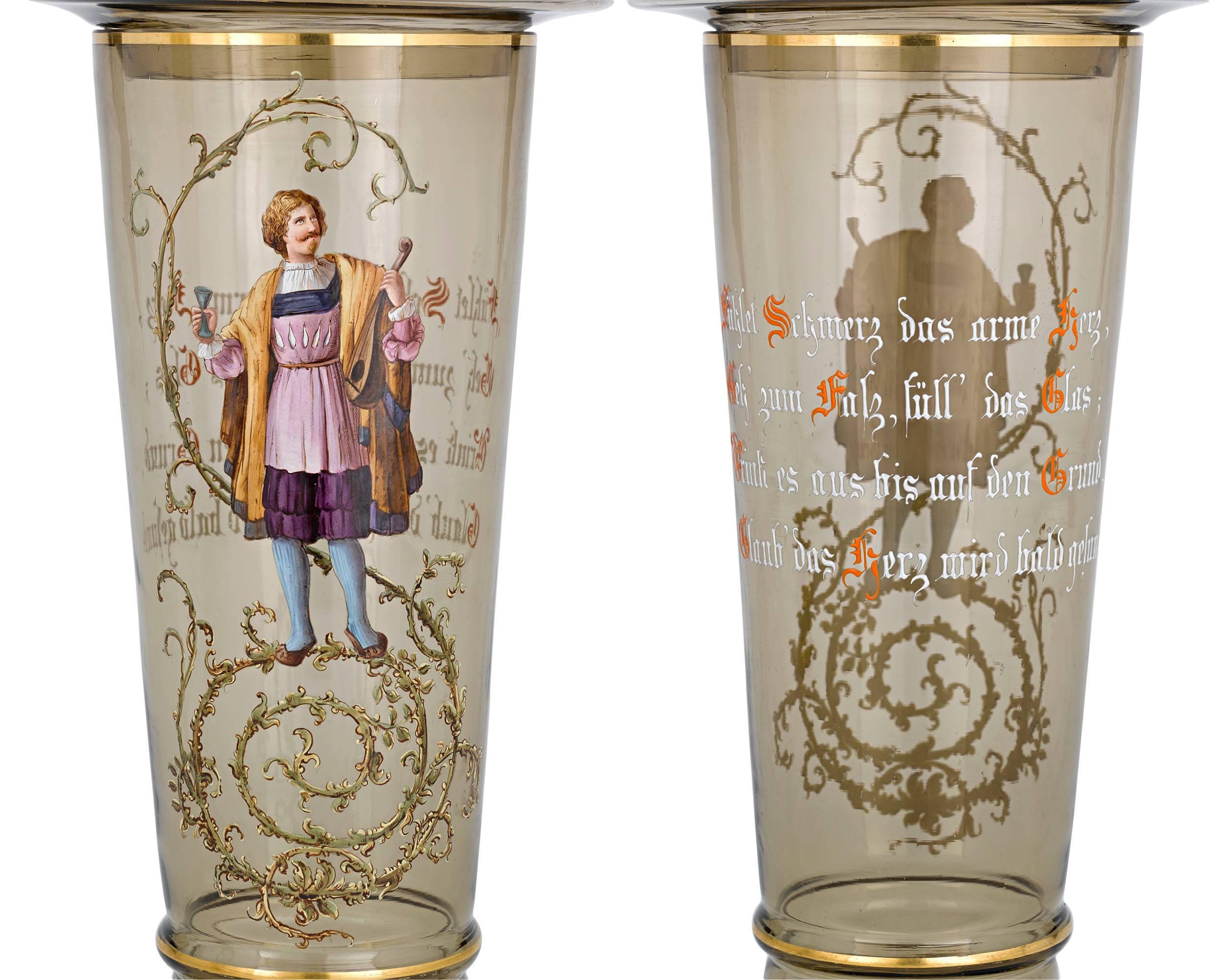 This rare pair of Moser covered goblets, or pokals are exquisitely hand-painted with figures in period clothing on the front and German text on the reverse. The German pokal is a large, tall, lidded goblet that is typically made of glass and