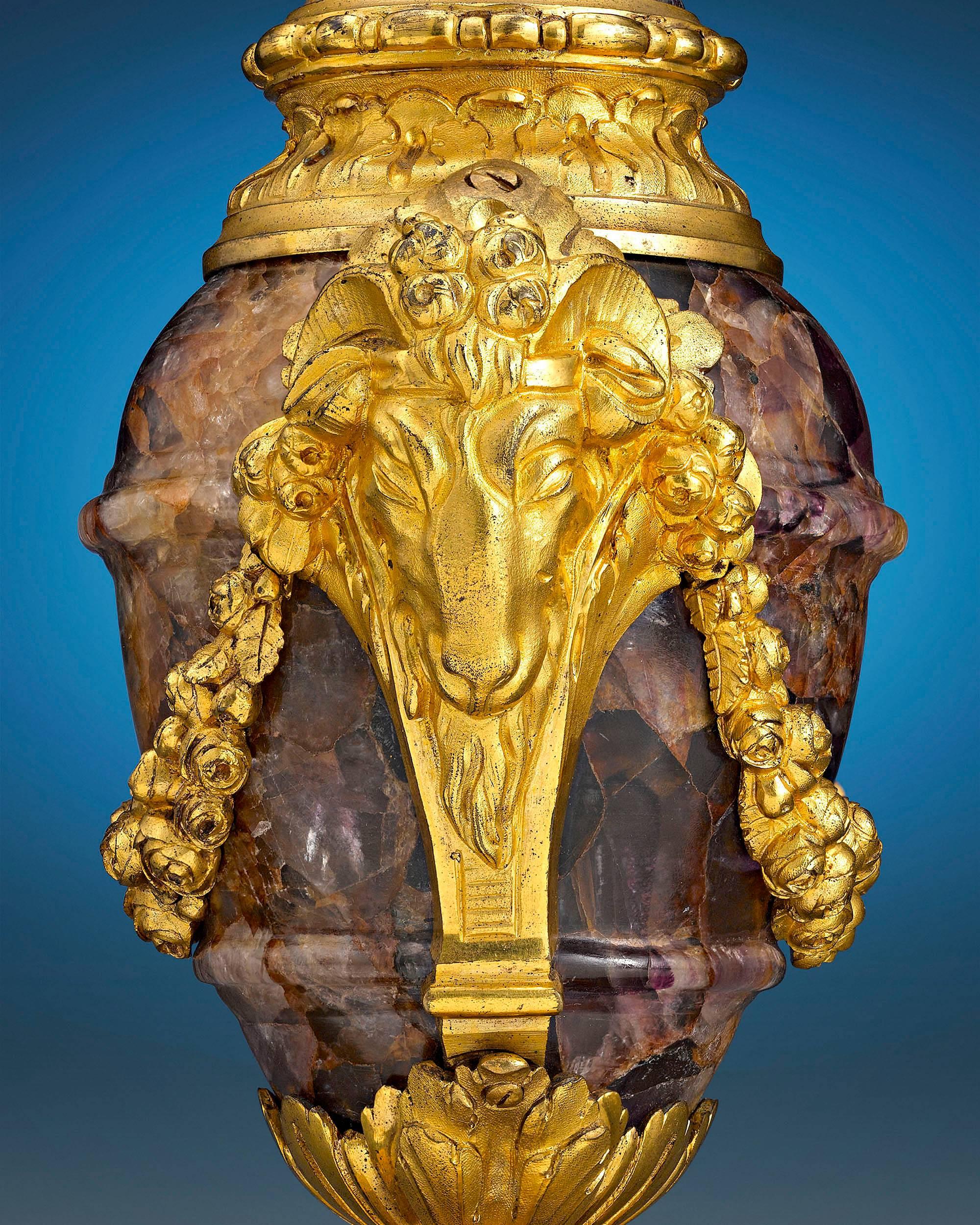 Mounted in resplendent ormolu, these remarkable and rare urns are crafted of Blue John, or Derbyshire Spar stone. Their forms are inspired by antiquity, with the now-extinct mineral's characteristic purple, blue and yellow grain contrasting
