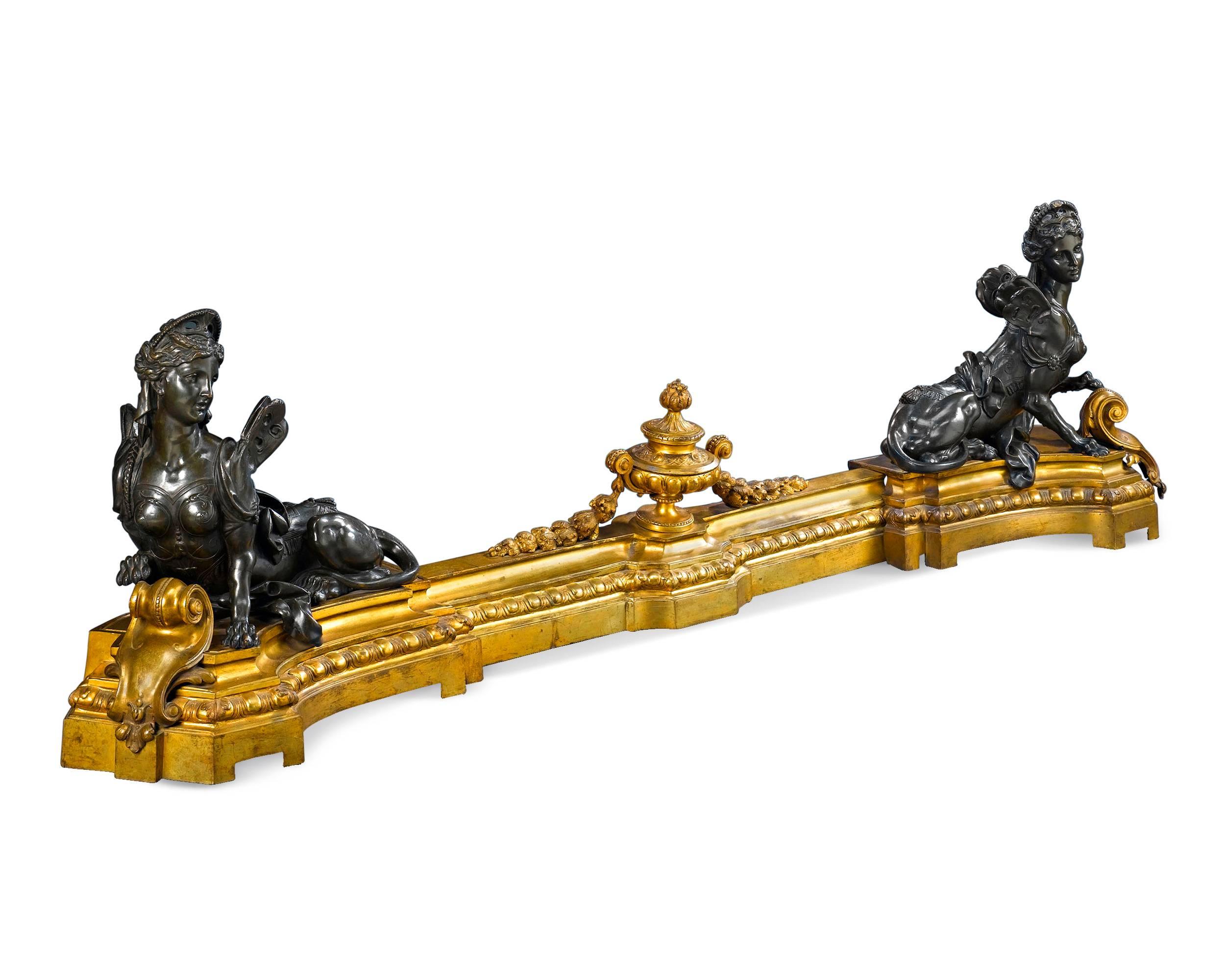 A pair of sphinx chenets guards this classical French ormolu fireplace guard. Cast from a model by renowned 19th century sculptor Frédérick Eugène Piat, the sphinxes rest upon a stepped fender surmounted by a floral-festooned urn. In a career