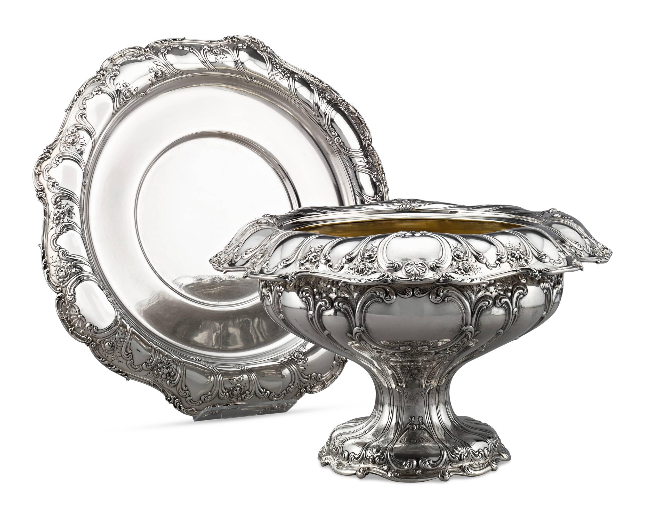 Detailed in an intricate repoussé and chased floral, scroll and shell motif is this exqusite silver punch bowl and under plate by the highly respected American silver smithing firm of Gorham. The Rhode Island firm is renowned for the high-caliber of