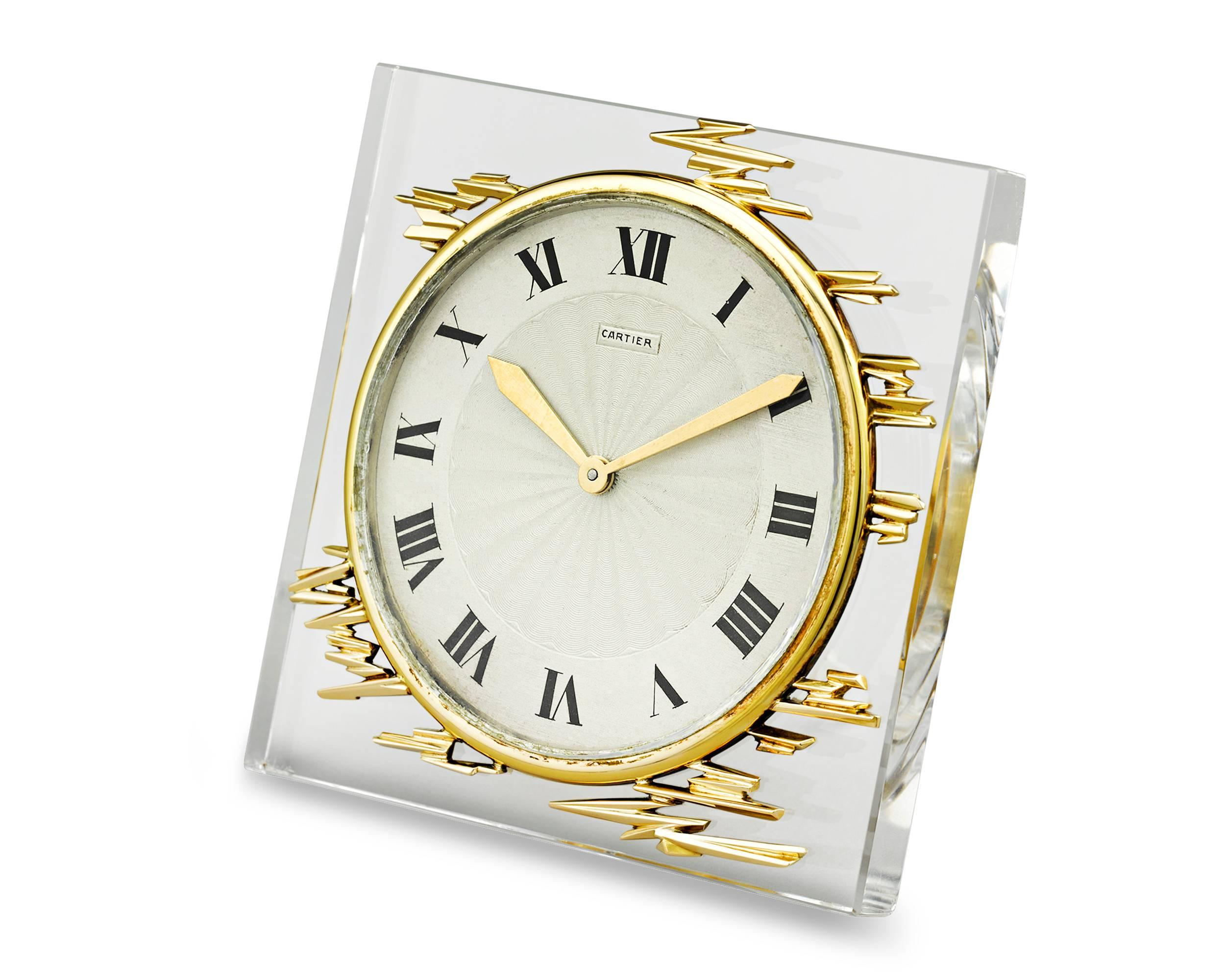 This rare and stylish desk clock epitomizes the timeless elegance of Cartier. Its sleek, retro design, featuring a crystal frame and golden accents, is immediately striking. Roman numerals mark the hours on the white enamel dial, while hands crafted