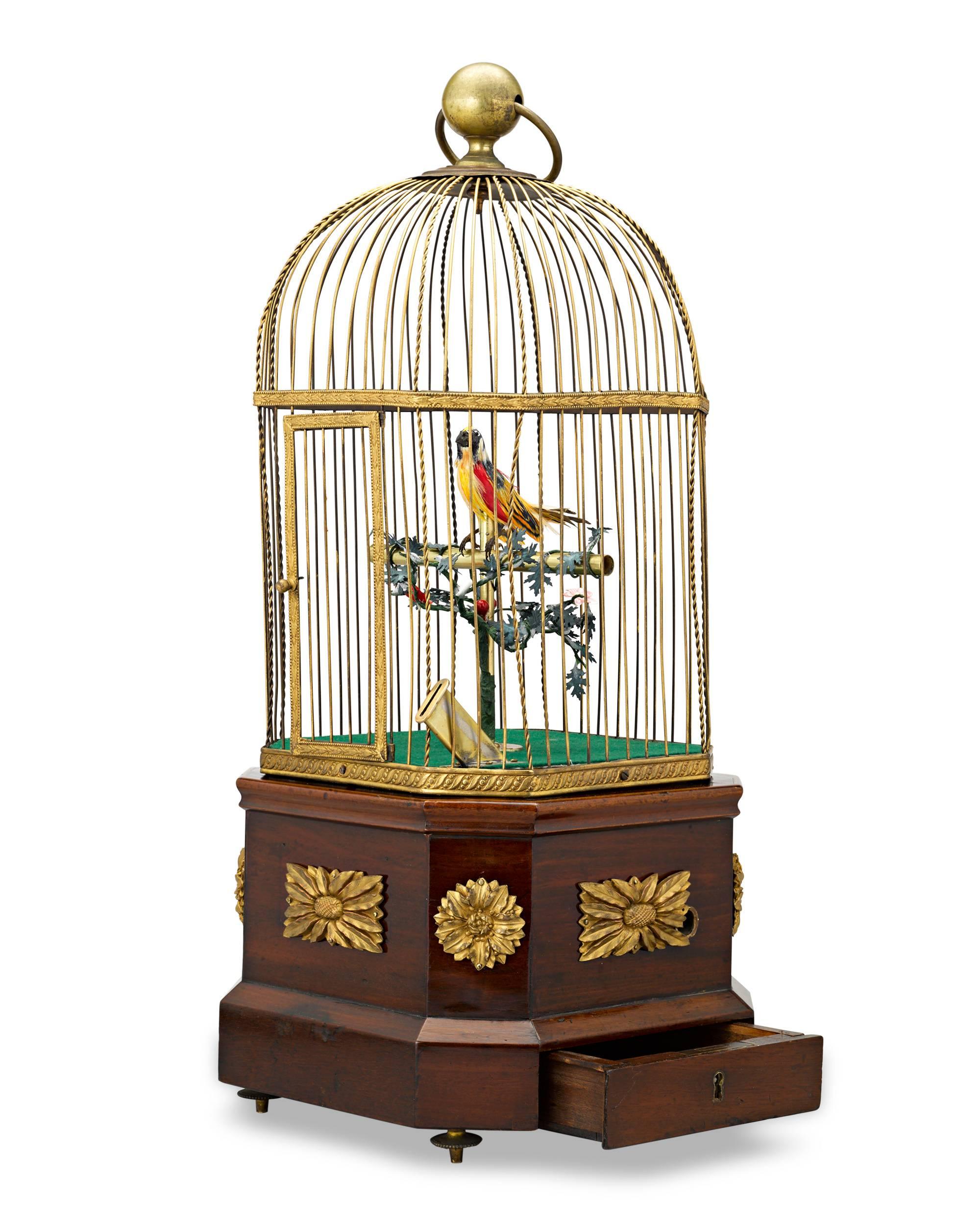 Hand-feathered in brilliant yellow and red is the diminutive mechanical bird inside its gilded cage. This delightful and rare singing bird automaton combines outstanding artistry with mechanical genius. The singing bird mechanism is itself a work of