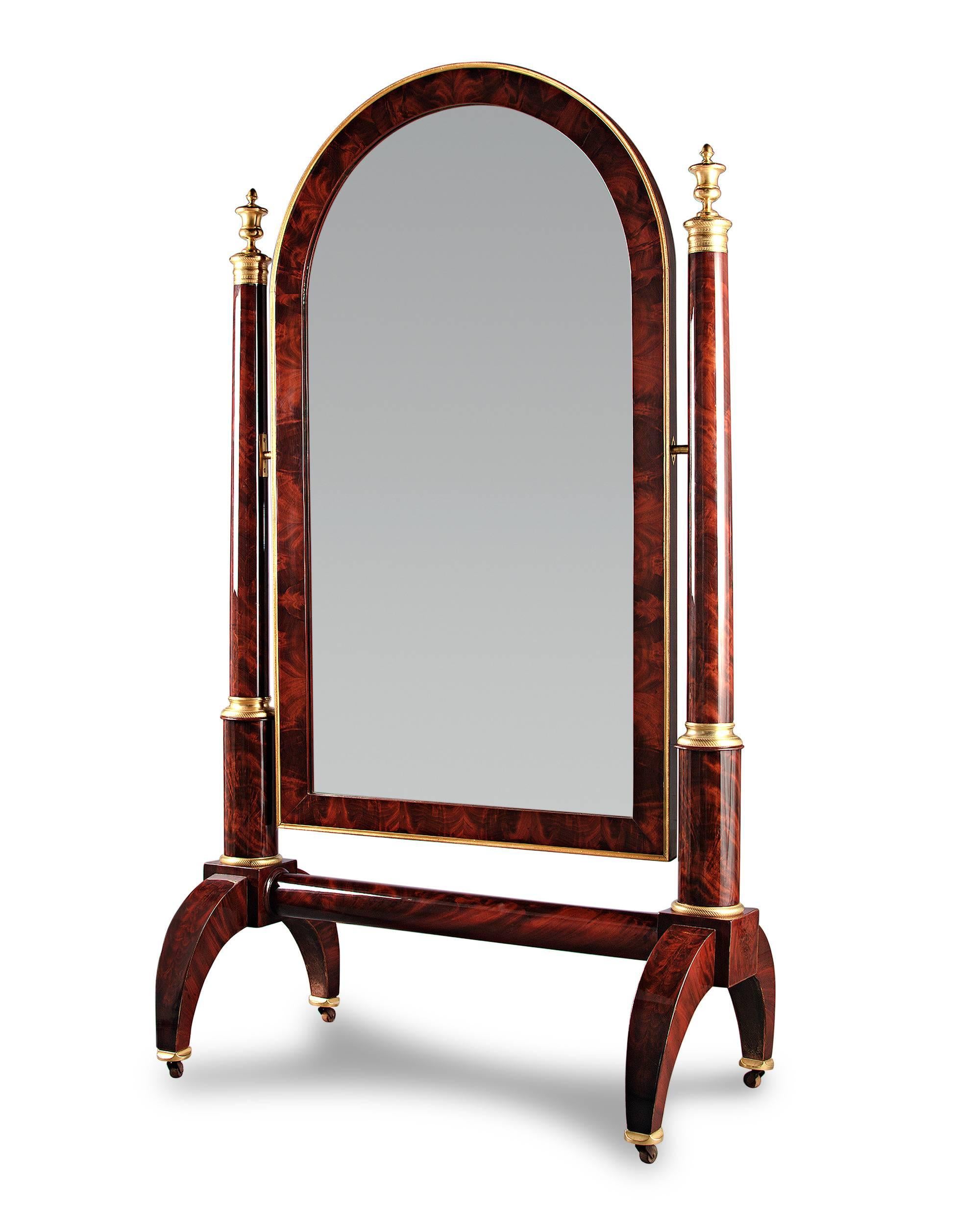 This magnificent French cheval mirror captures the luxury of the Empire period in grand style. Crafted of mahogany, the period piece is graced by intricate doré bronze mounts that embody the classically-inspired style of the Napoléonic era. Elegant