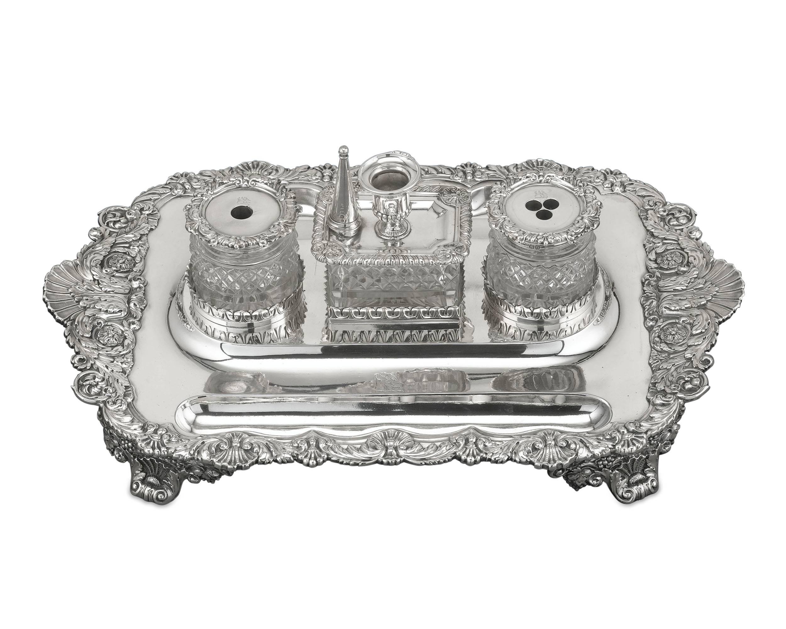 This magnificent silver inkstand by the preeminent silversmith Paul Storr is a work of Georgian elegance. Exhibiting an exuberant design of flowers, scallop shells and rolling acanthus this magnificent set is comprised of three cut-glass jars,