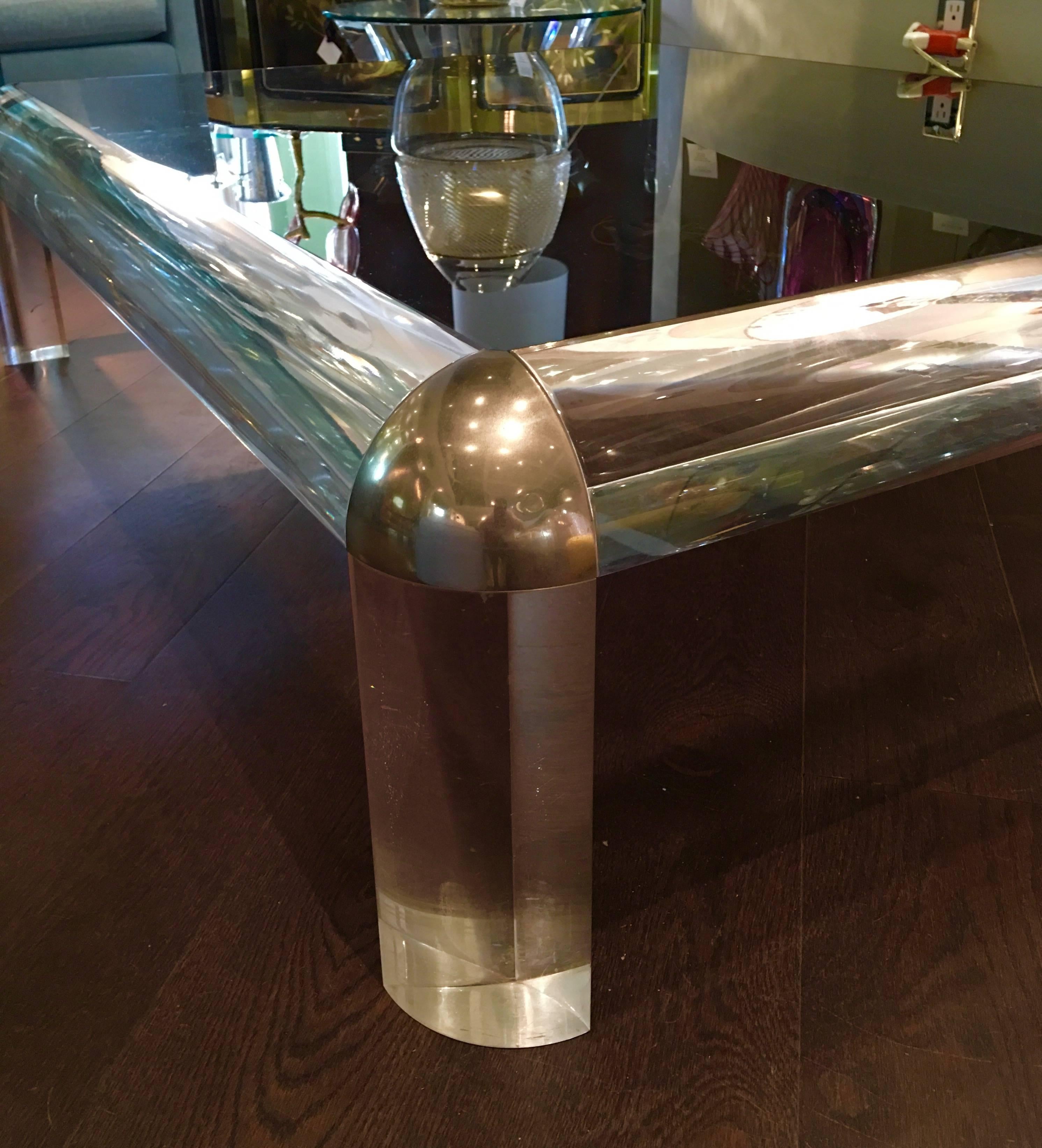 This Glamorous Hollywood Regency coffee table in the style of  Karl Springer has thick heavy column legs and triangle capped chrome corners. The original smoked glass top adds to the different elements. It is rectangular with radius corners, 1970s.