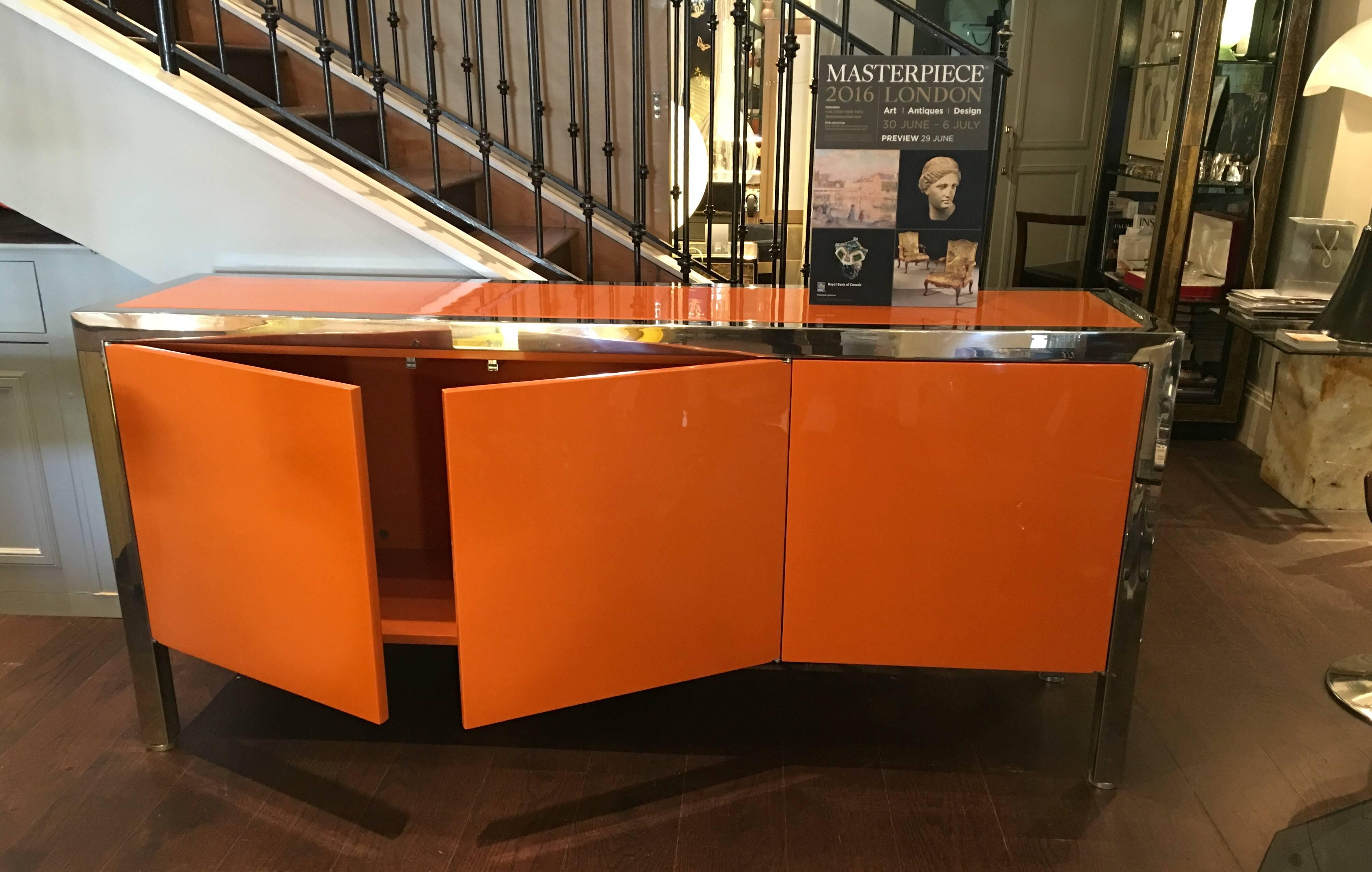 A wonderful Pace sideboard/cabinet with brilliant orange lacquer finish. Heavy polished steel frame supports the cabinet on every side.