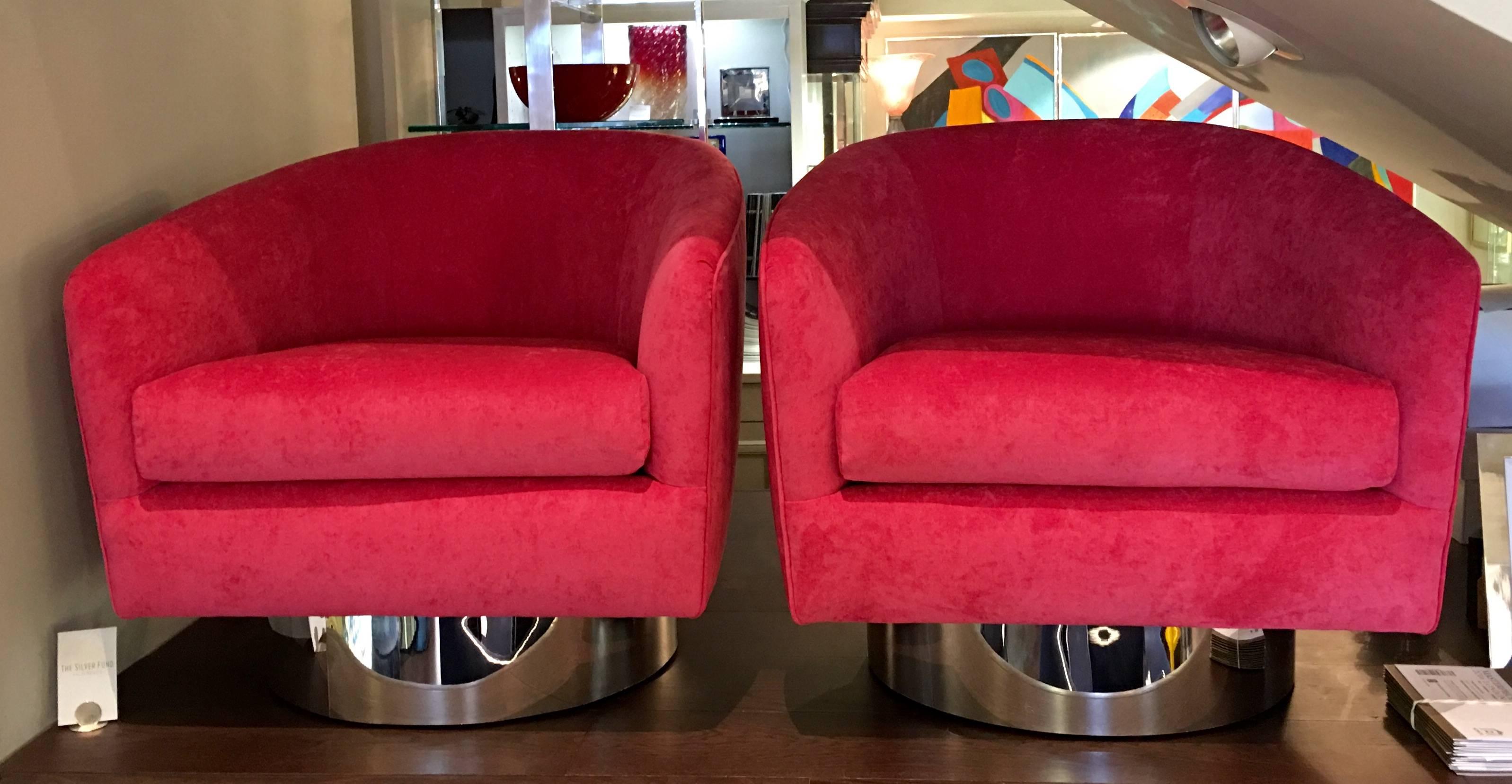 A pair of swivel lounge chairs attributed to Milo Baughman. Each chair has a circular chrome base, newly upholstered in beautiful pink velvet fabric.