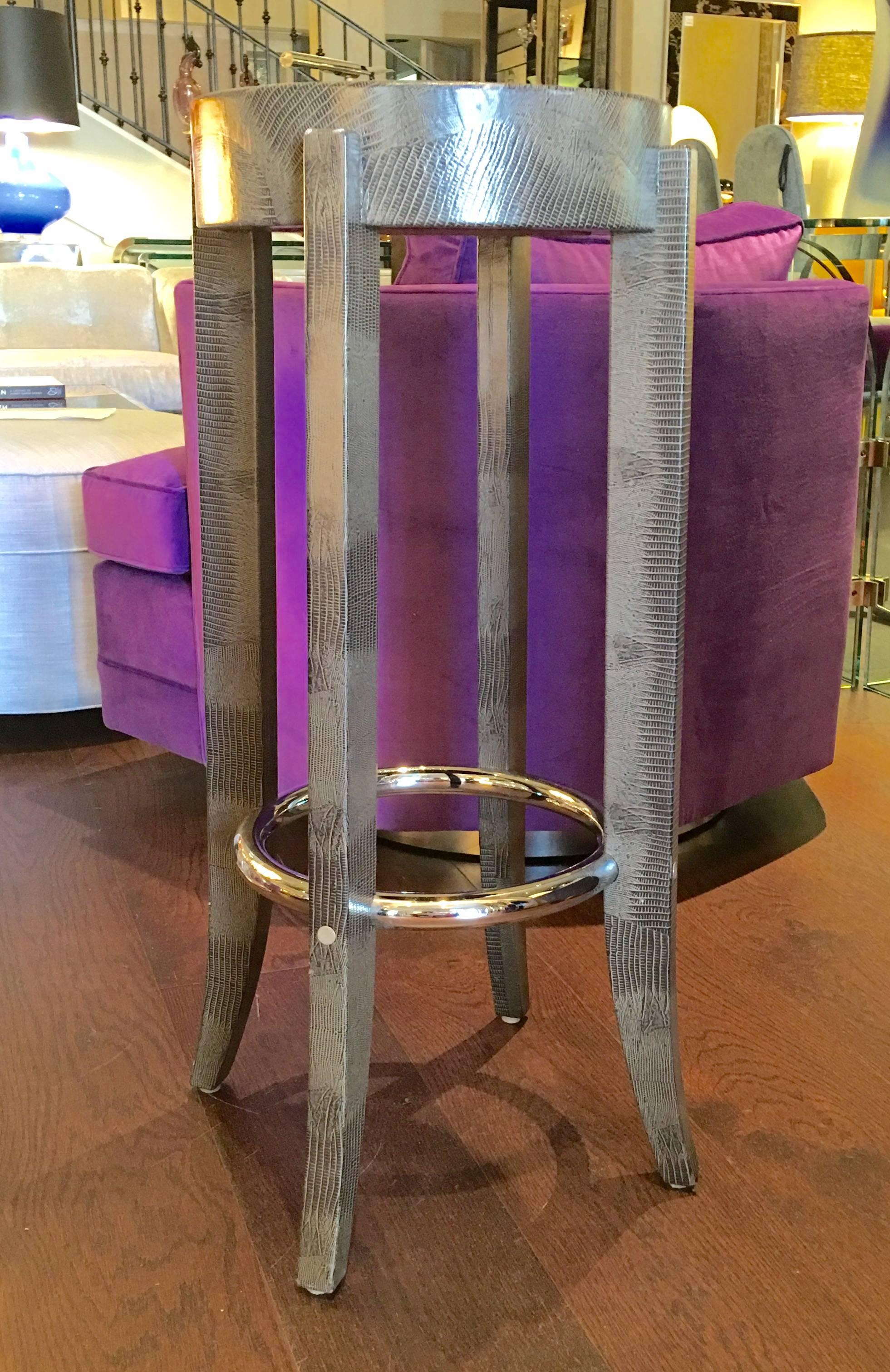 A fabulous pair of bar stools signed by designer Karl Springer covered in faux lizard skin and chrome ring.