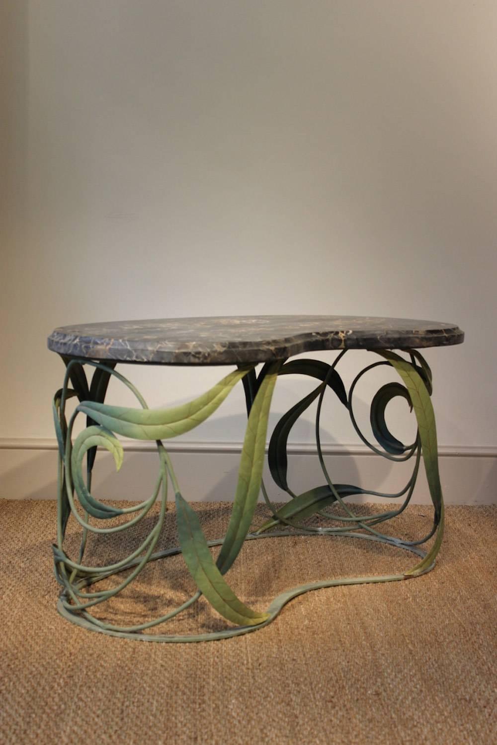 A highly unusual French green-painted wrought and sheet metal occasional table or coffee table, the base modelled as scrolling entwined leaves, with a moulded kidney-shaped portor marble top.