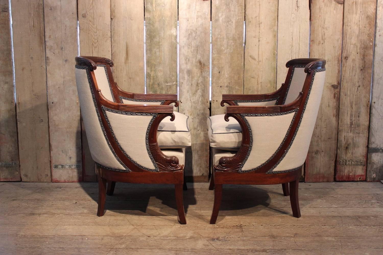 A good quality pair of Louis Philippe carved mahogany and upholstered bergere armchairs with reeded backs and arms, and dolphin-carved supports, with excellent colour