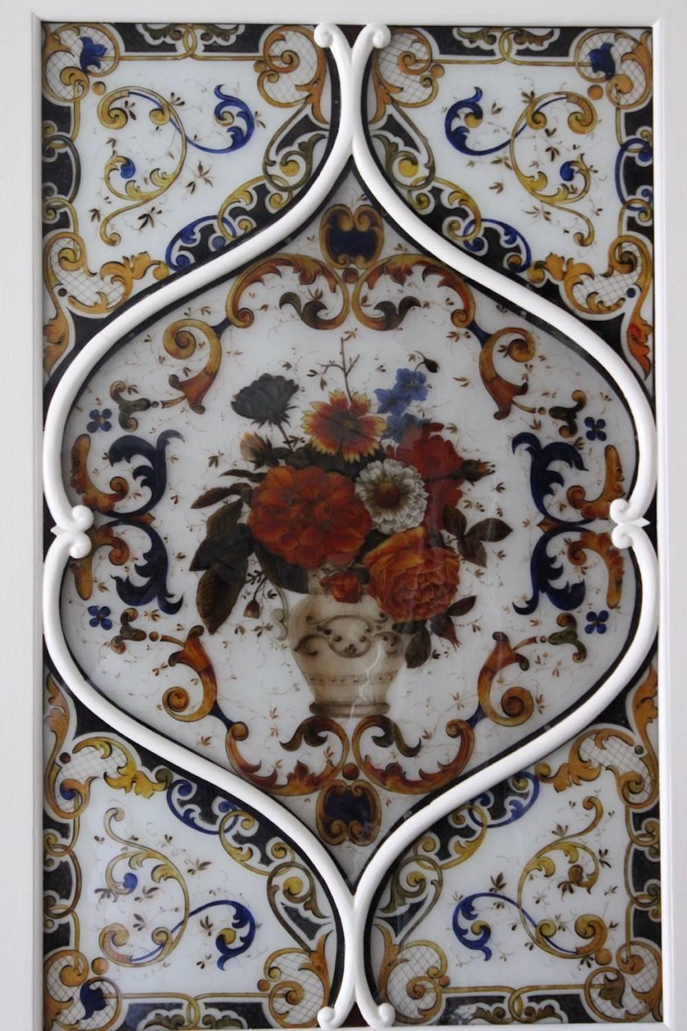 A charming and highly decorative pair of painted glass panels, the central reserve of each depicting vases with an abundance of flowers, in white-painted, pierced and carved frames (probably originally part of an architectural facade), Italian,