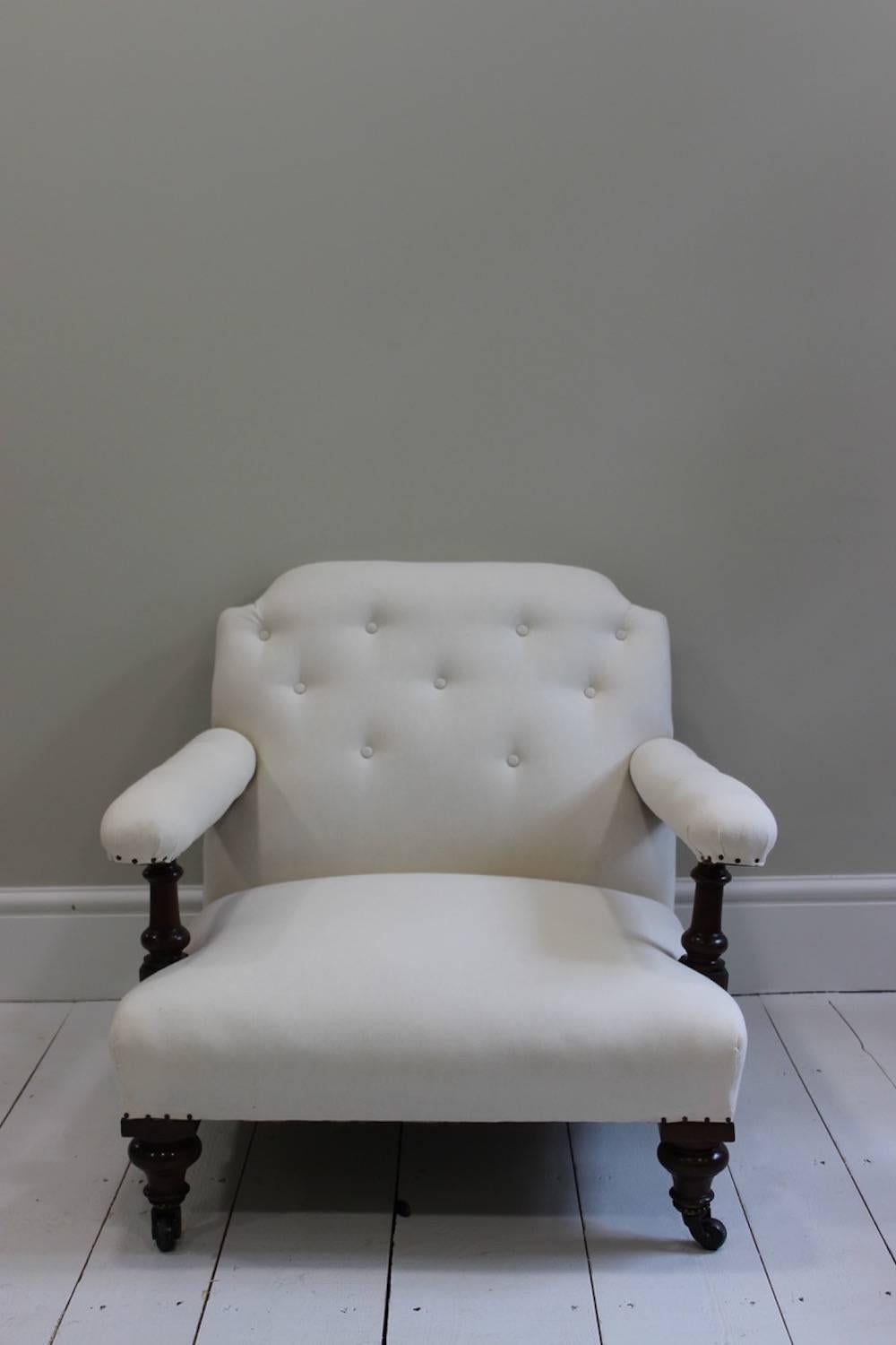 A smart and comfortable mid-19th century English low armchair, the mahogany frame with turned legs and castors, re-upholstered in calico with a buttoned back.