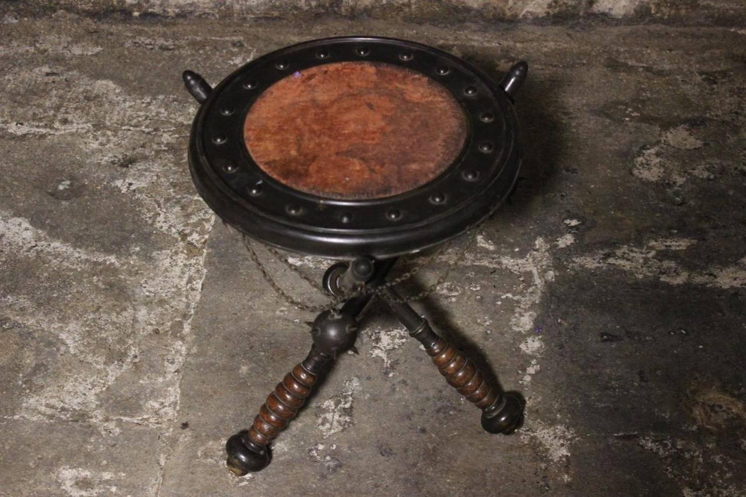 An unusual and interesting late 19th century cast metal circular occasional table in the form of three maces supporting a shield, the top with original inset fabric lining, English, circa 1870.